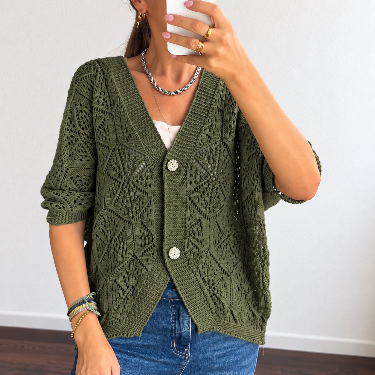 Cardigan verde caqui de malha com padrão aberto e botões, usado com acessórios dourados e calças de ganga azul
