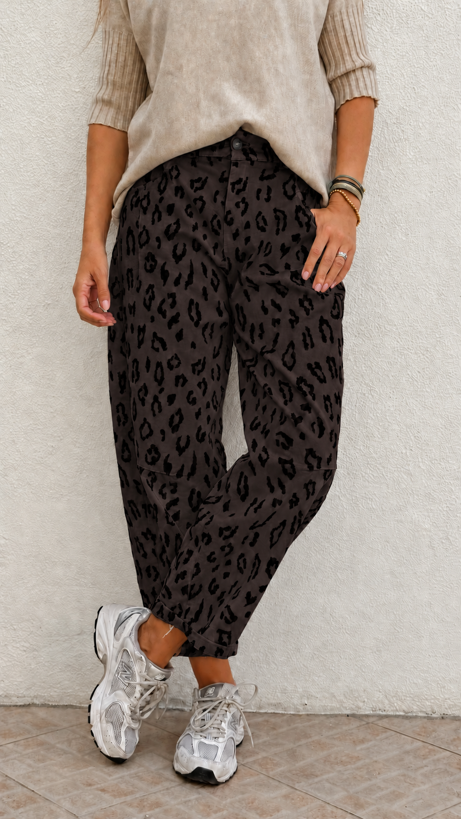 Calças animal print cinza escuro com top bege e sapatilhas brancas em ambiente interior
