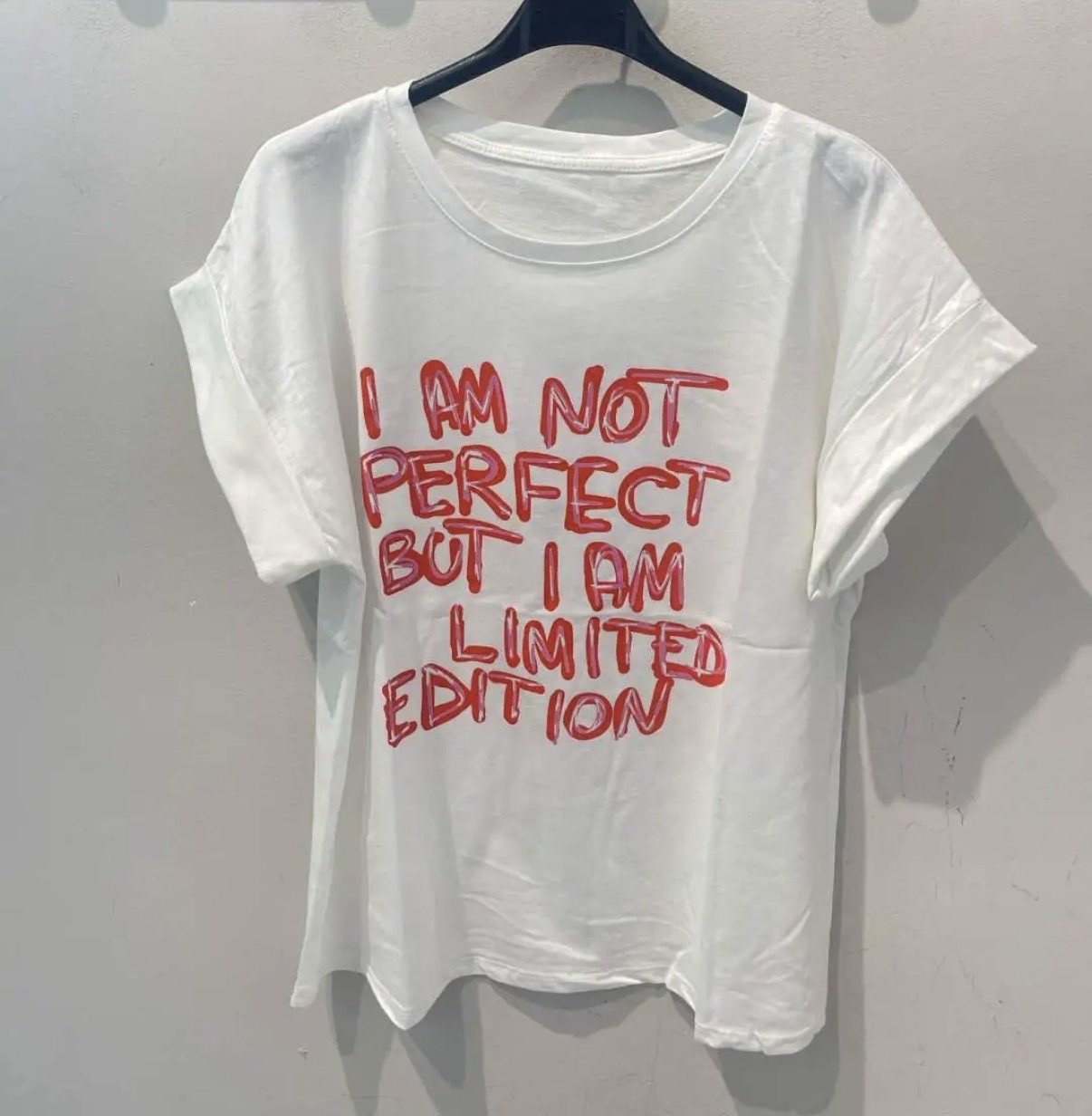 T-shirt branca com texto vermelho pendurada num cabide preto