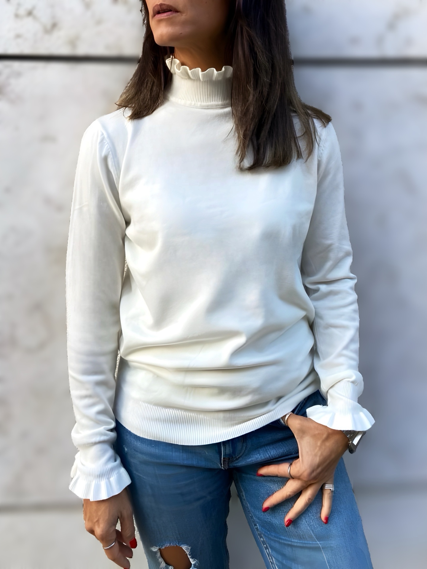 Camisola branca feminina com gola e punhos frisados e jeans azul claro rasgados