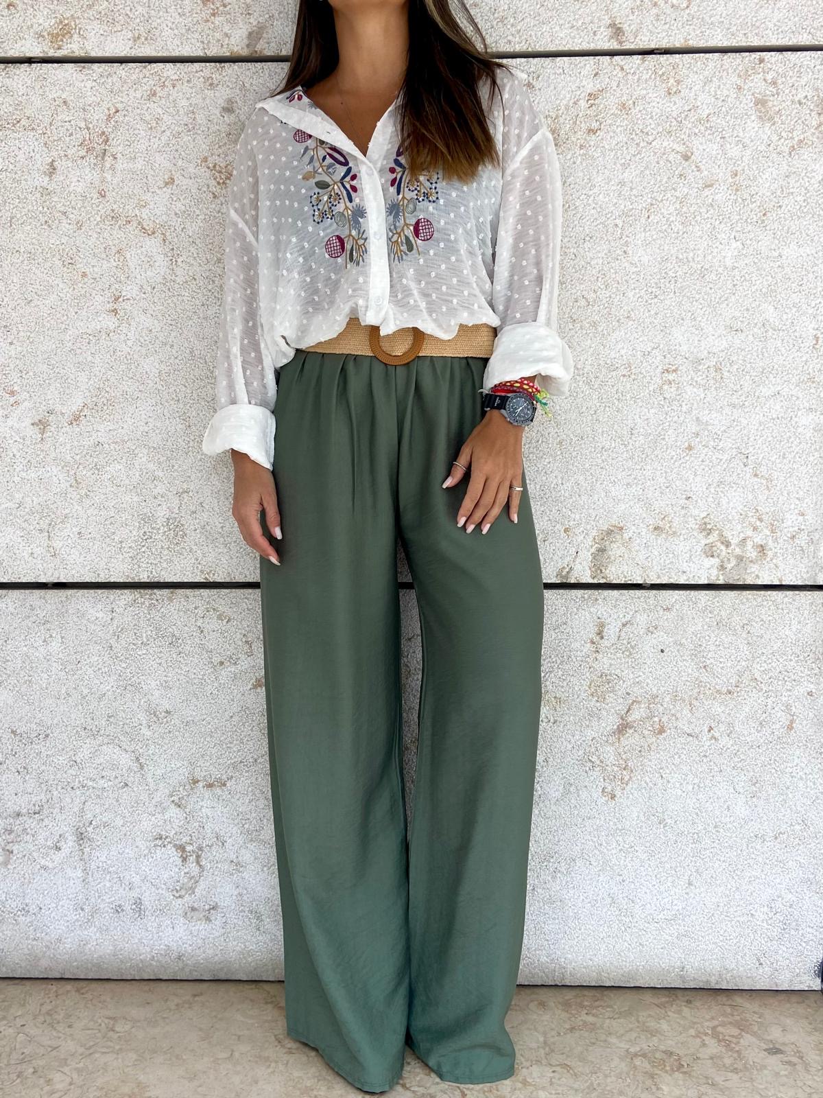 Pessoa com blusa branca bordada e calças largas verdes