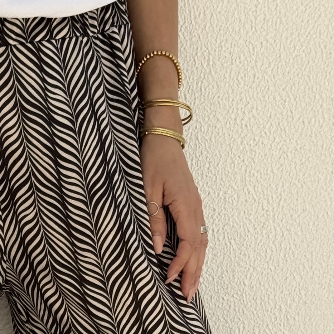 Saia ou vestido preto e branco com pulseiras douradas e anéis prateados