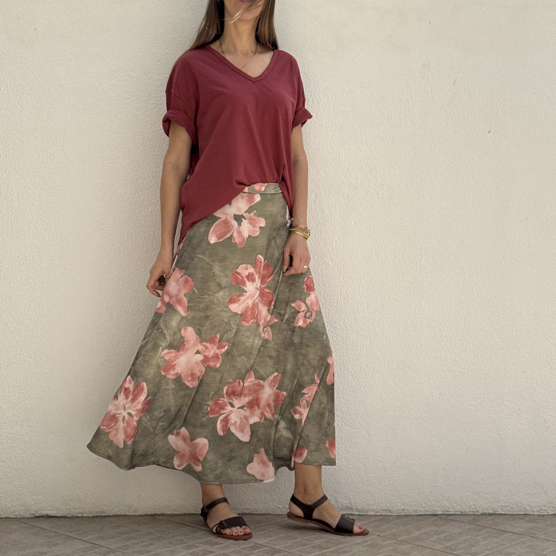 Mulher veste saia longa floral verde e rosa, t-shirt vinho com decote, sandálias castanhas