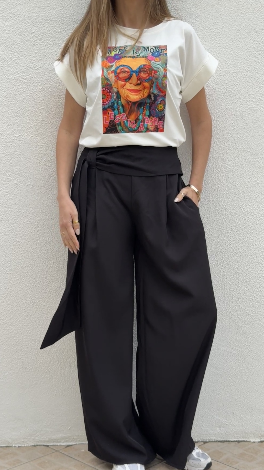 Pessoa com t-shirt branca estampada com rosto colorido e calças pretas largas