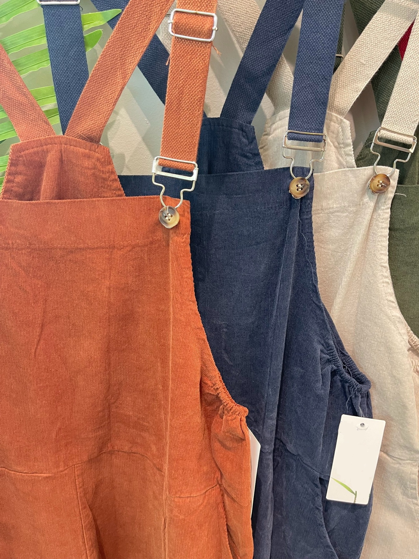 Jardineiras de veludo cotelê em três cores diferentes penduradas