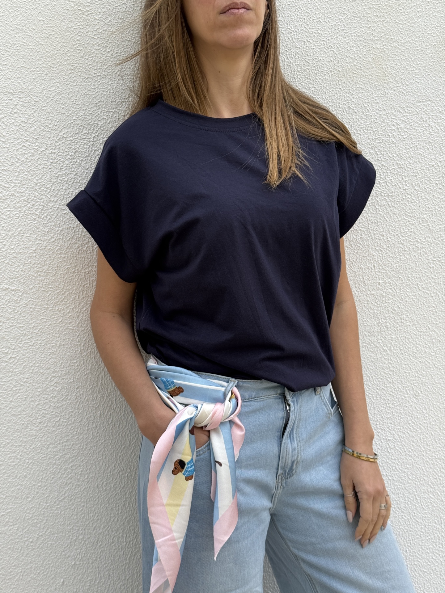 Mulher vestindo t-shirt preta e calças de ganga claras com lenço colorido amarrado no cinto