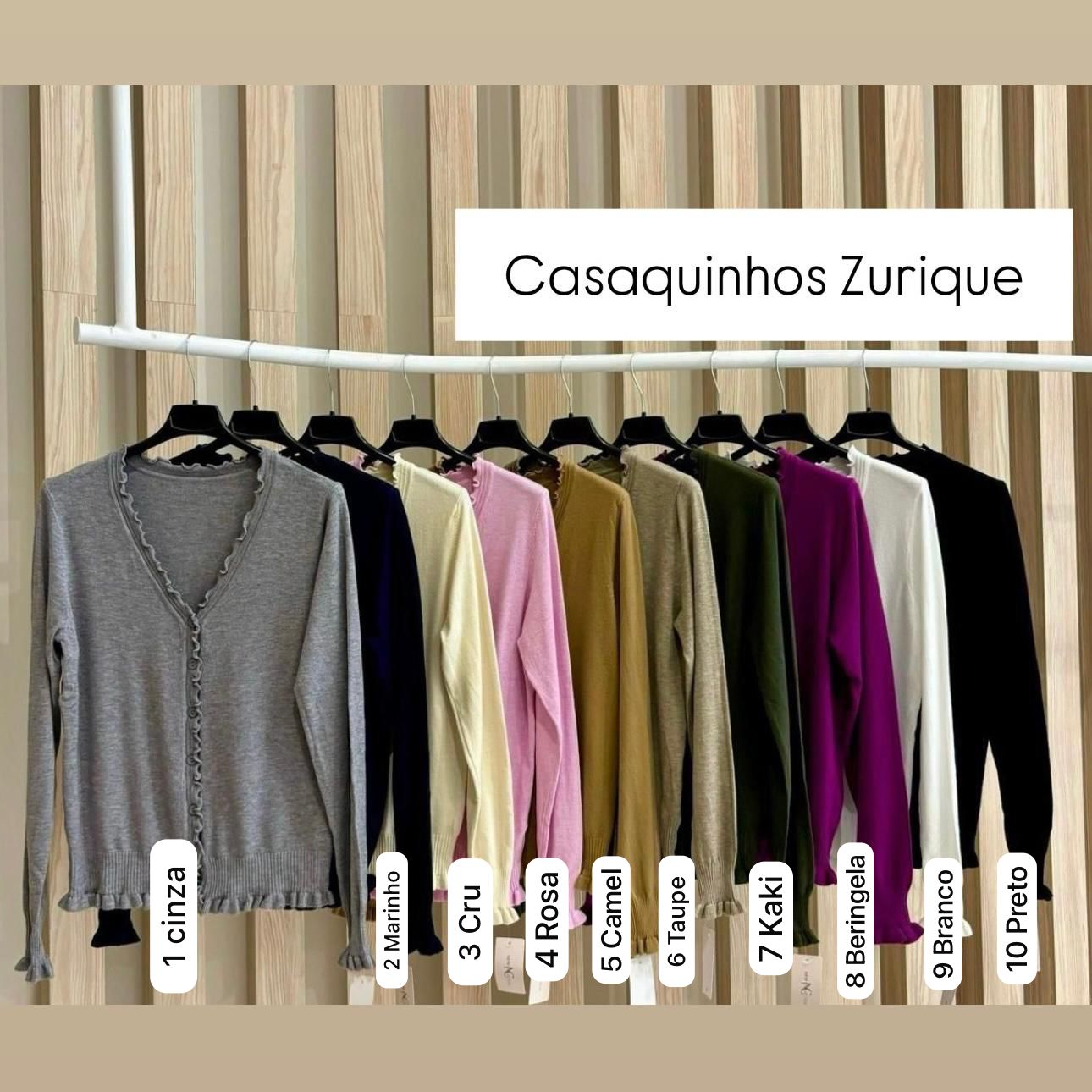 Coleção de casaquinhos em várias cores pendurados em cabides pretos contra fundo de painéis de madeira