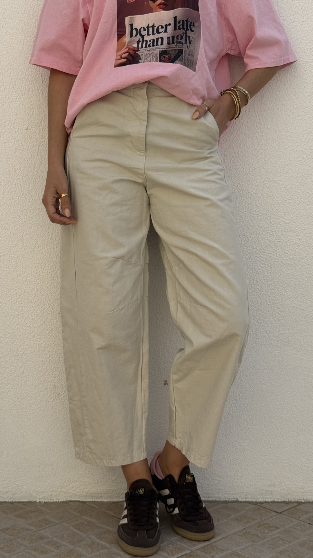 Pessoa com calças bege largas, sapatos pretos e t-shirt rosa com estampa