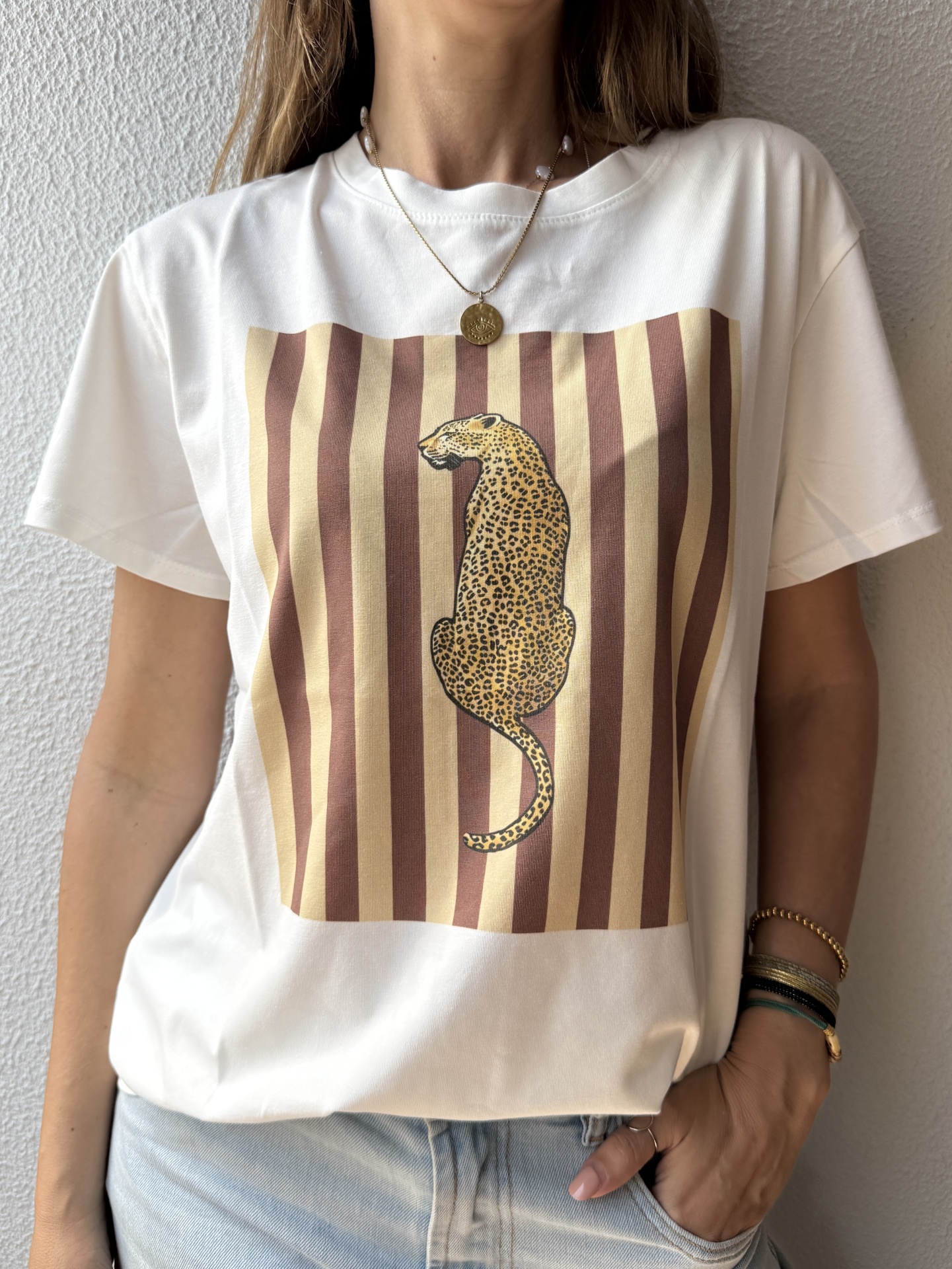 T-shirt branca com estampa de leopardo sobre riscas castanhas e bege.
