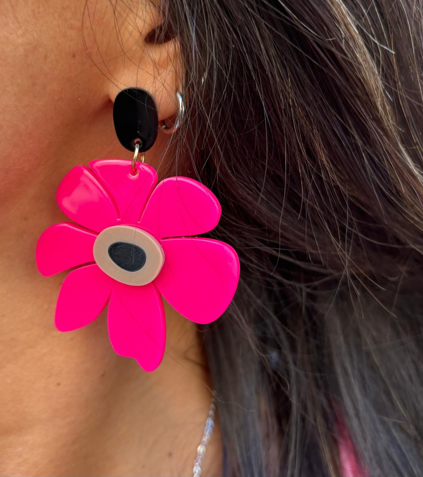Brinco em forma de flor cor-de-rosa com centro bege e preto pendurado na orelha