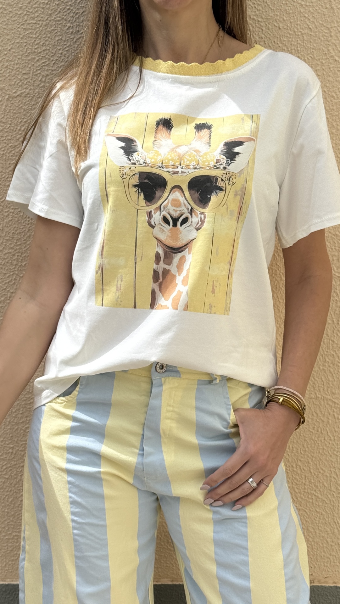 T-shirt branca com estampa de girafa e calças riscas amarelas e azuis