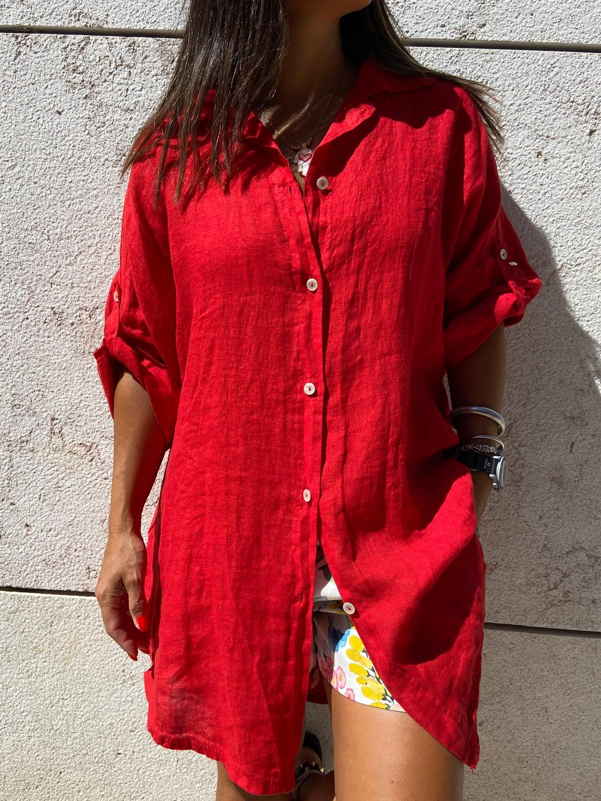 Camisa comprida vermelha com botões e mangas arregaçadas, usada com calções florais