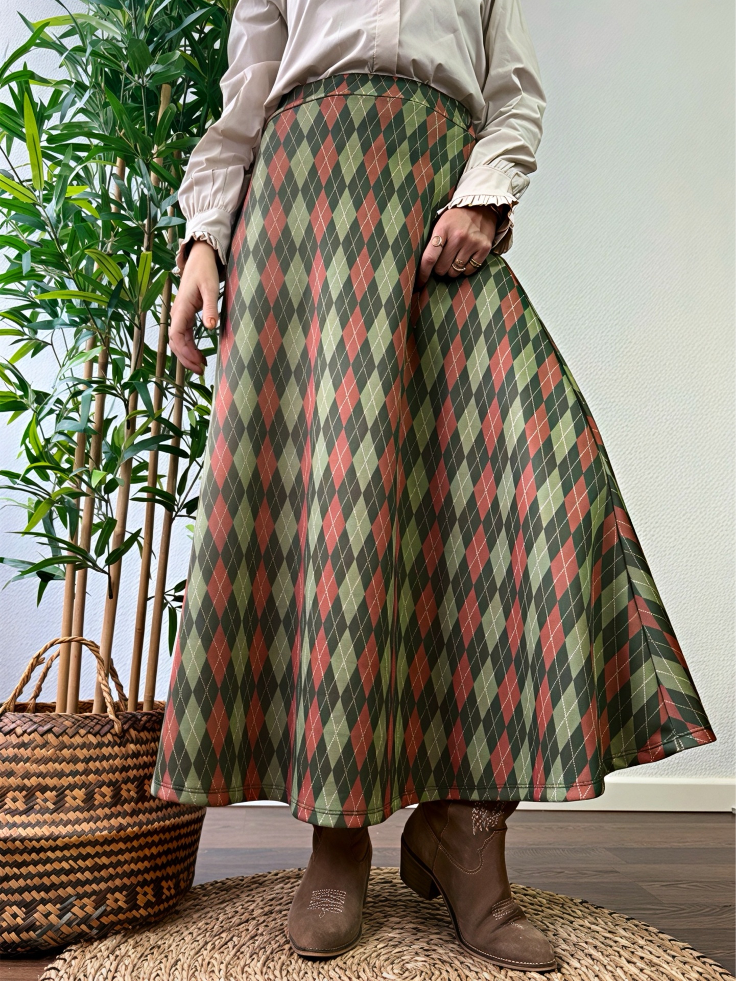 Saia comprida com padrão de losangos em verde, castanho e terracota com botins castanhos em ambiente interior
