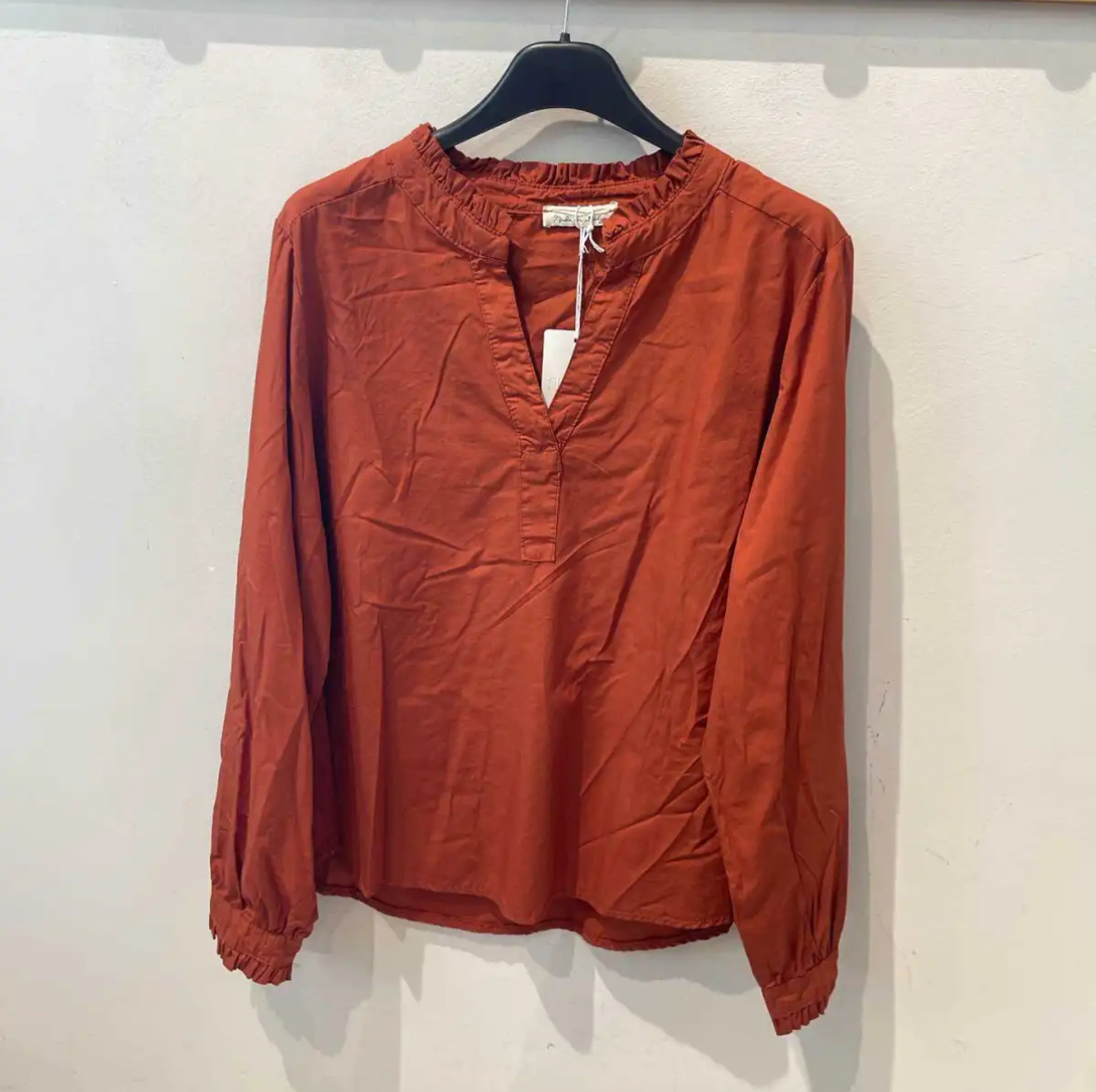 Blusa ferrugem de manga comprida com gola e punhos franzidos pendurada