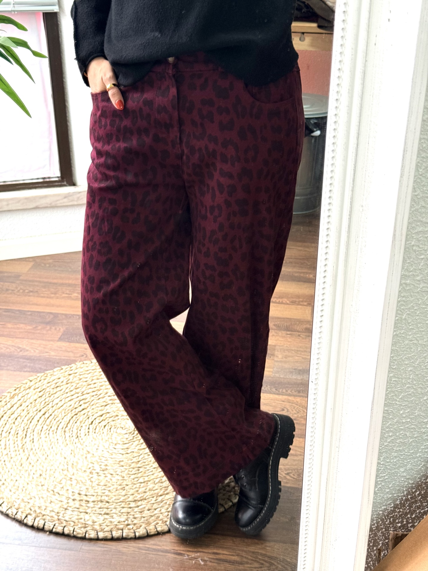 Calças rosa escuro com padrão leopardo e botas pretas usadas em interior com chão de madeira