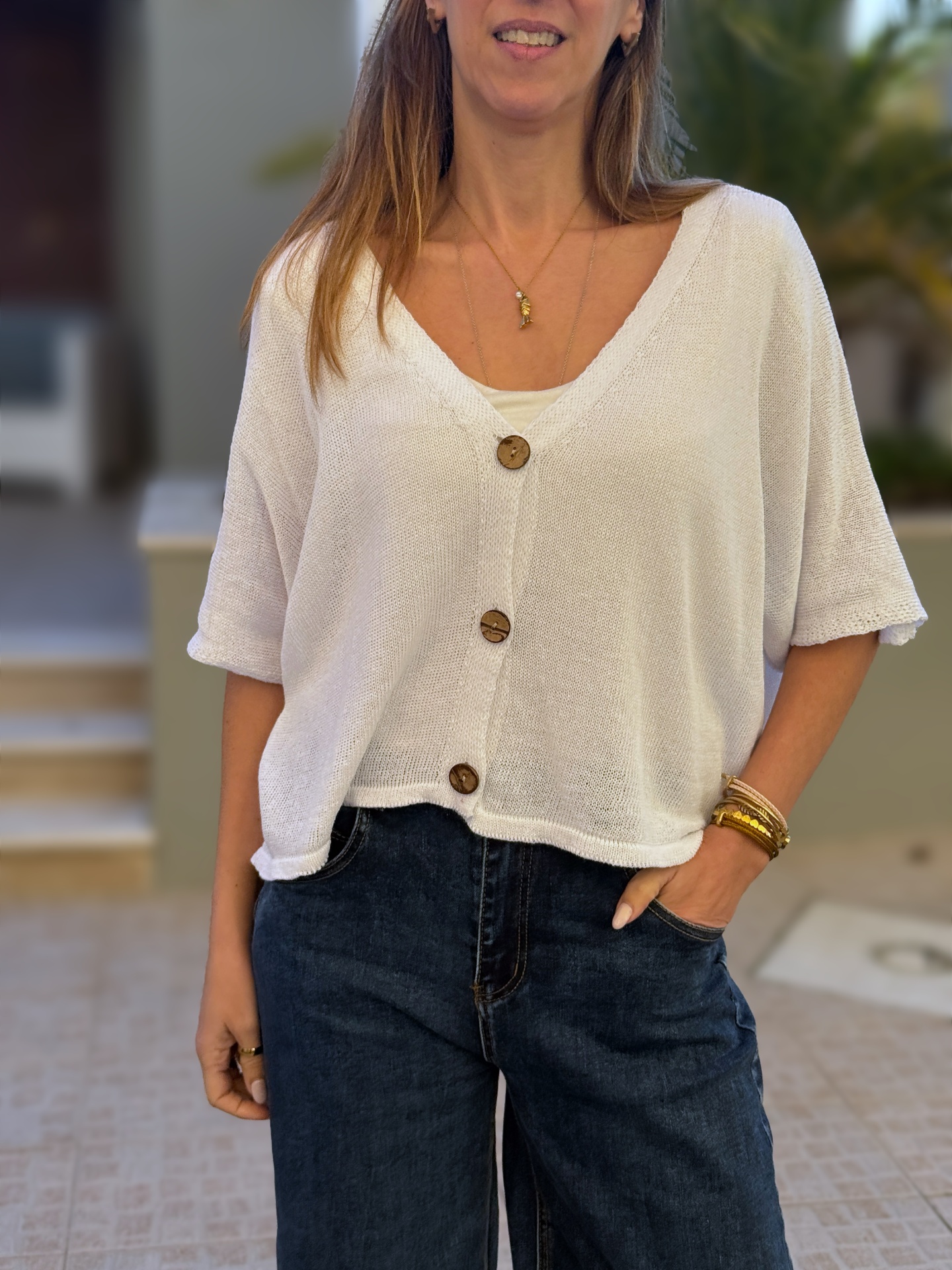 Camisola branca de malha com botões castanhos e calças jeans escuras