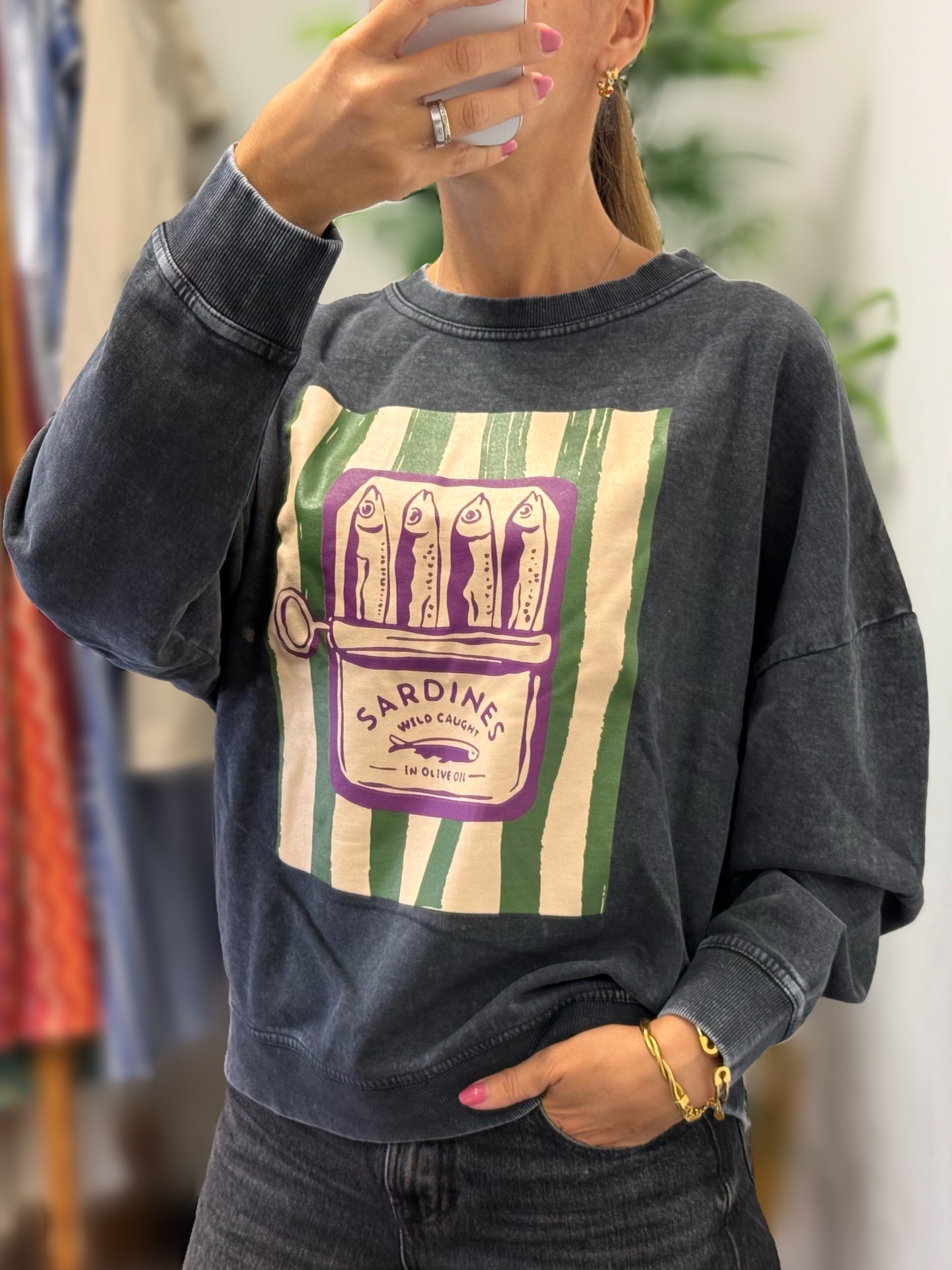 Sweatshirt cinzenta escura com estampa de lata de sardinhas em verde, creme e roxo.