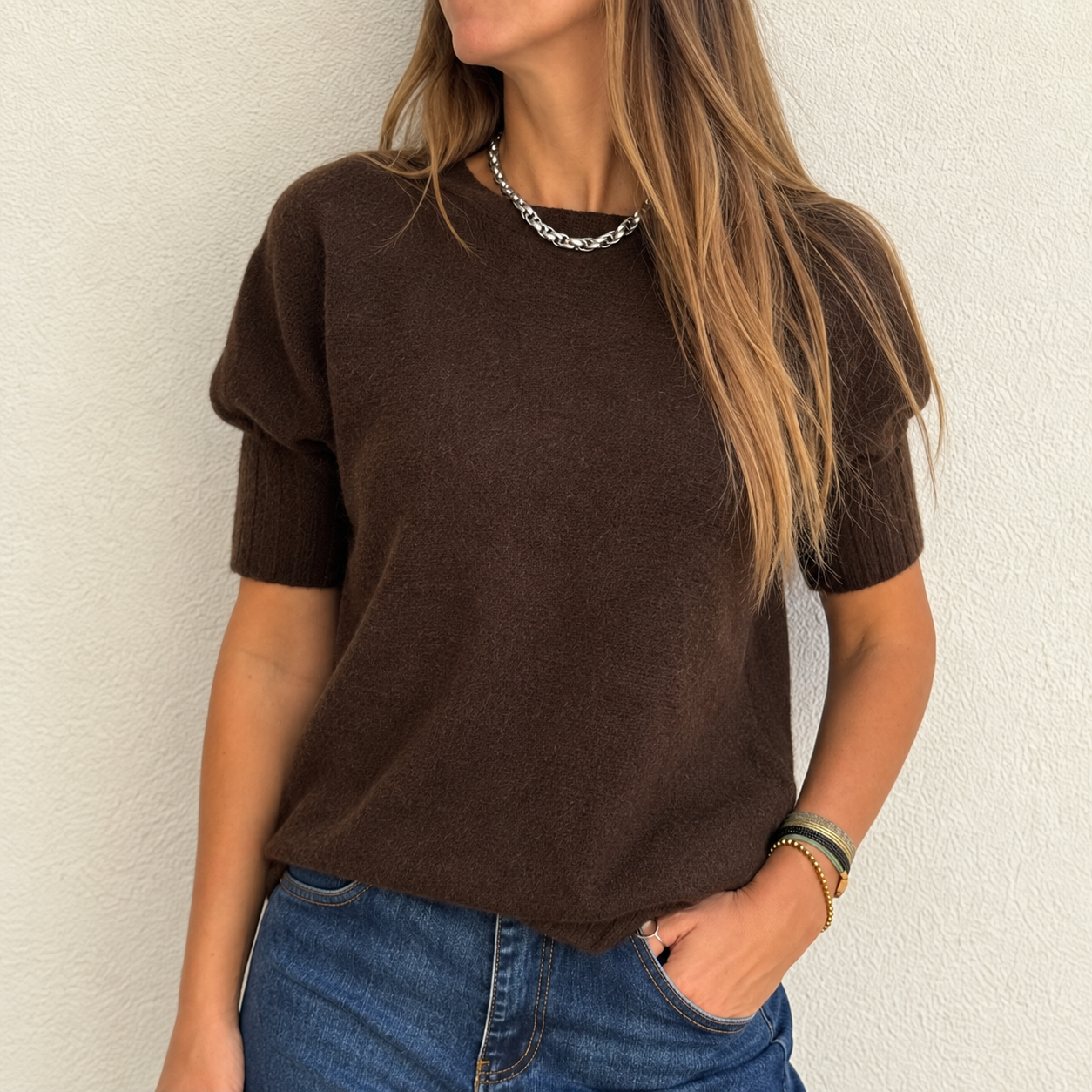 Camisola de malha castanha de manga curta com detalhes bufantes e jeans azuis