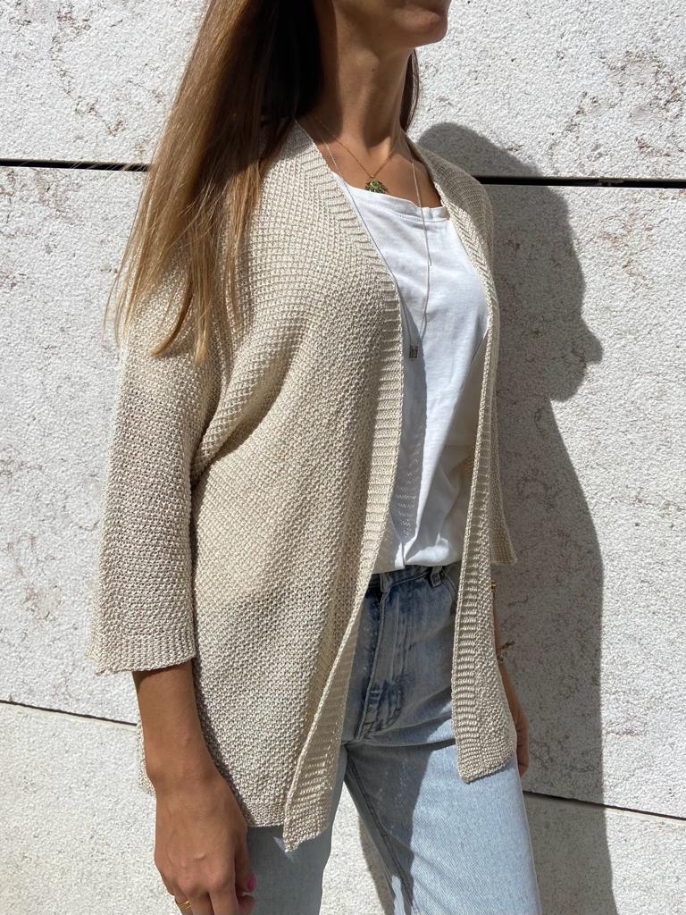 Cardigã bege de malha com textura, usado com t-shirt branca e jeans azuis