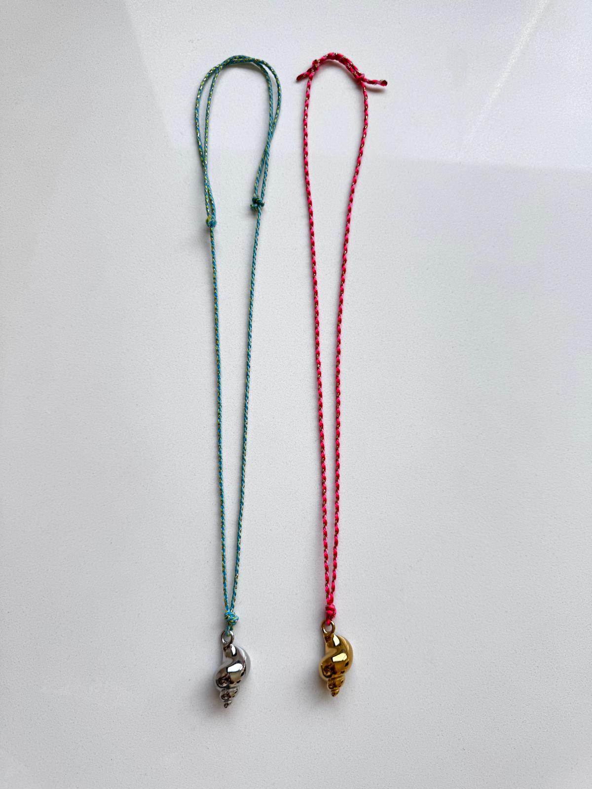Duas pulseiras com cordel trançado verde e rosa e pendentes em forma de conchas prateado e dourado
