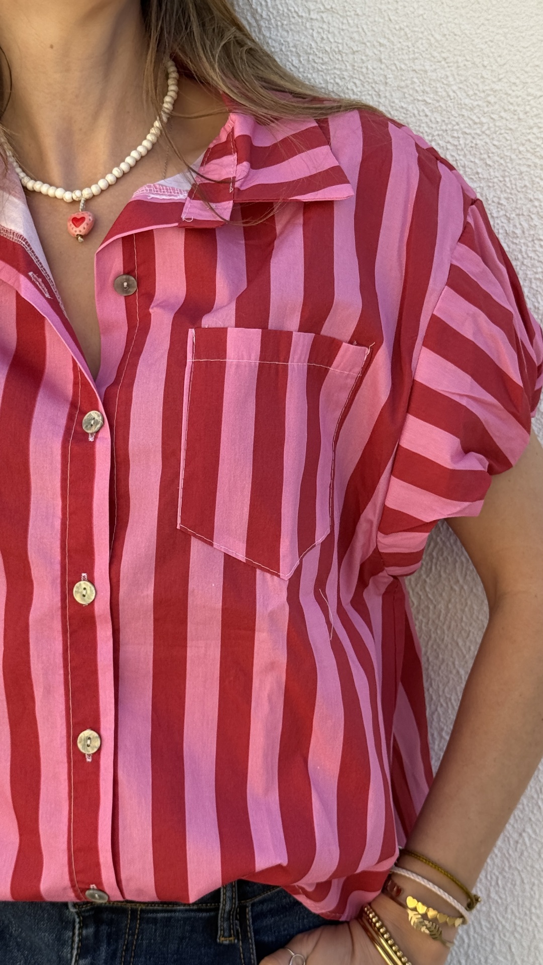 Camisa riscada em vermelho e rosa com bolso, botões, jeans e acessórios