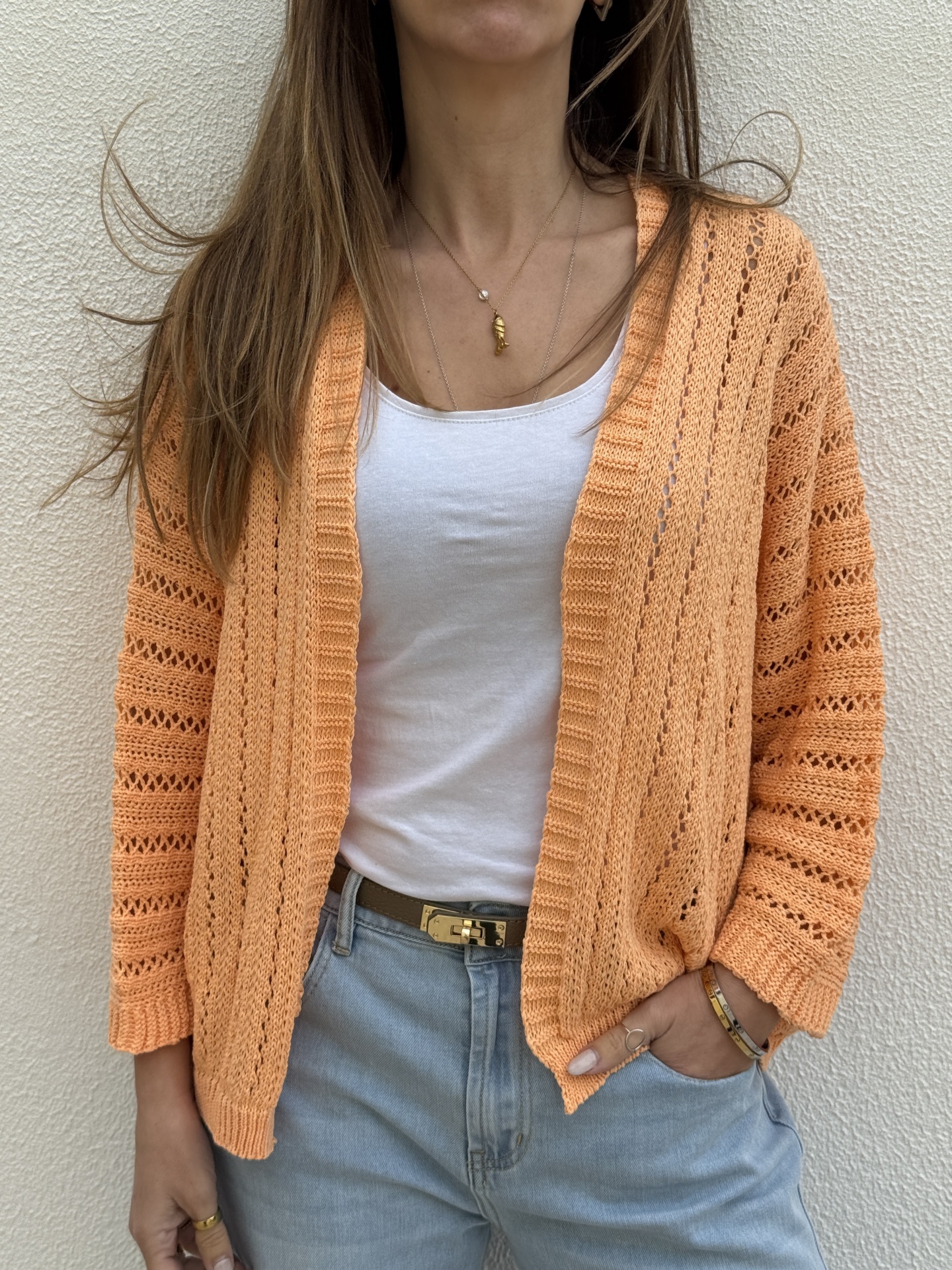 Cardigan de malha laranja perfurada com t-shirt branca e calças de ganga