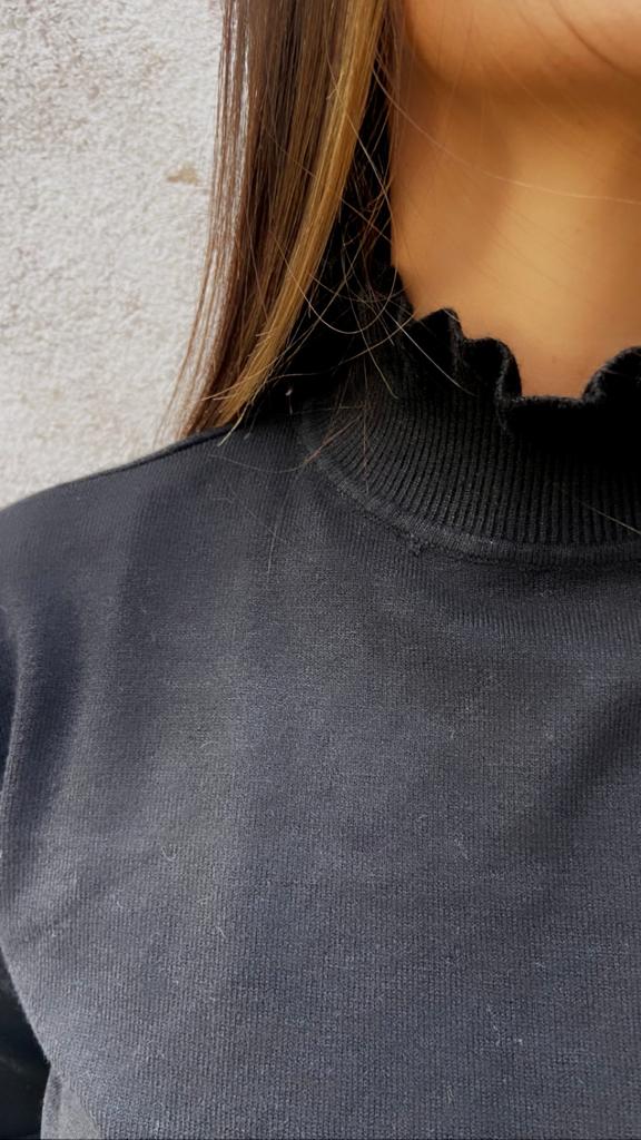 Camisola preta com gola canelada ondulada em fundo claro
