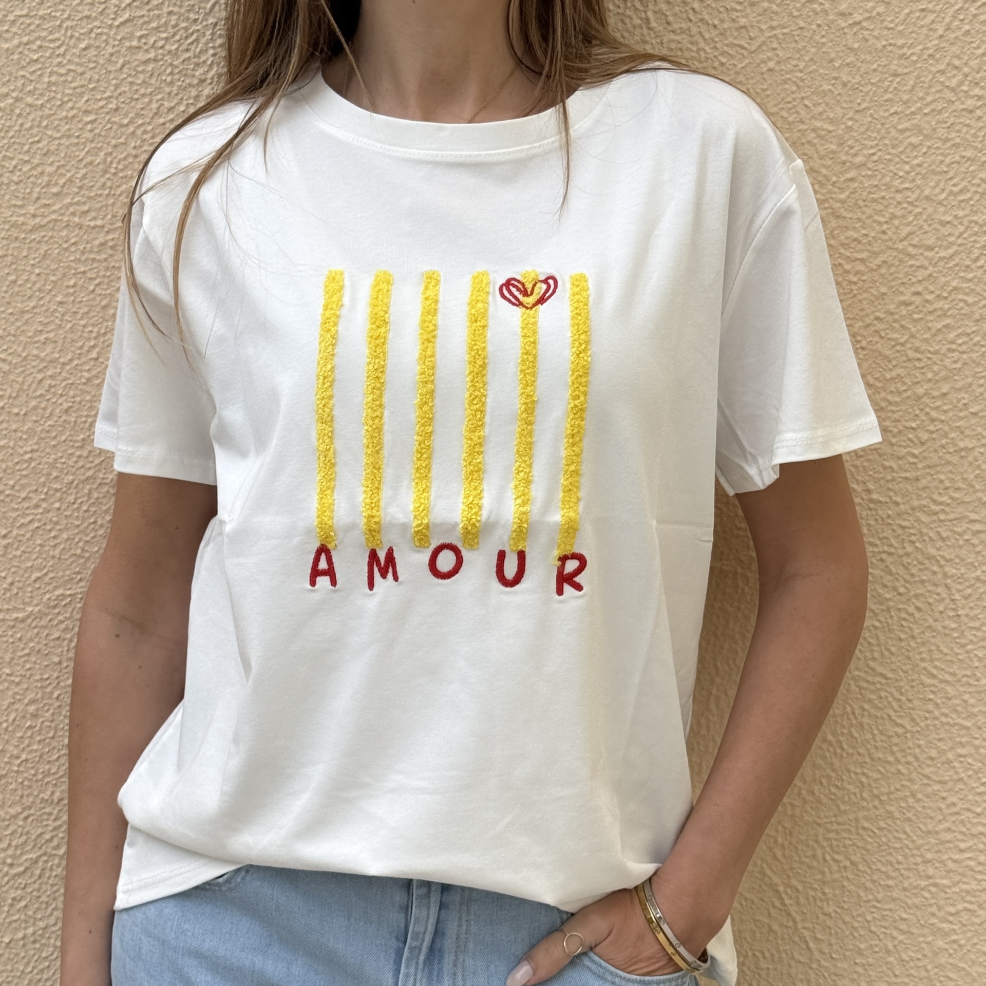 T-shirt branca com estampado amarelo e texto vermelho AMOUR