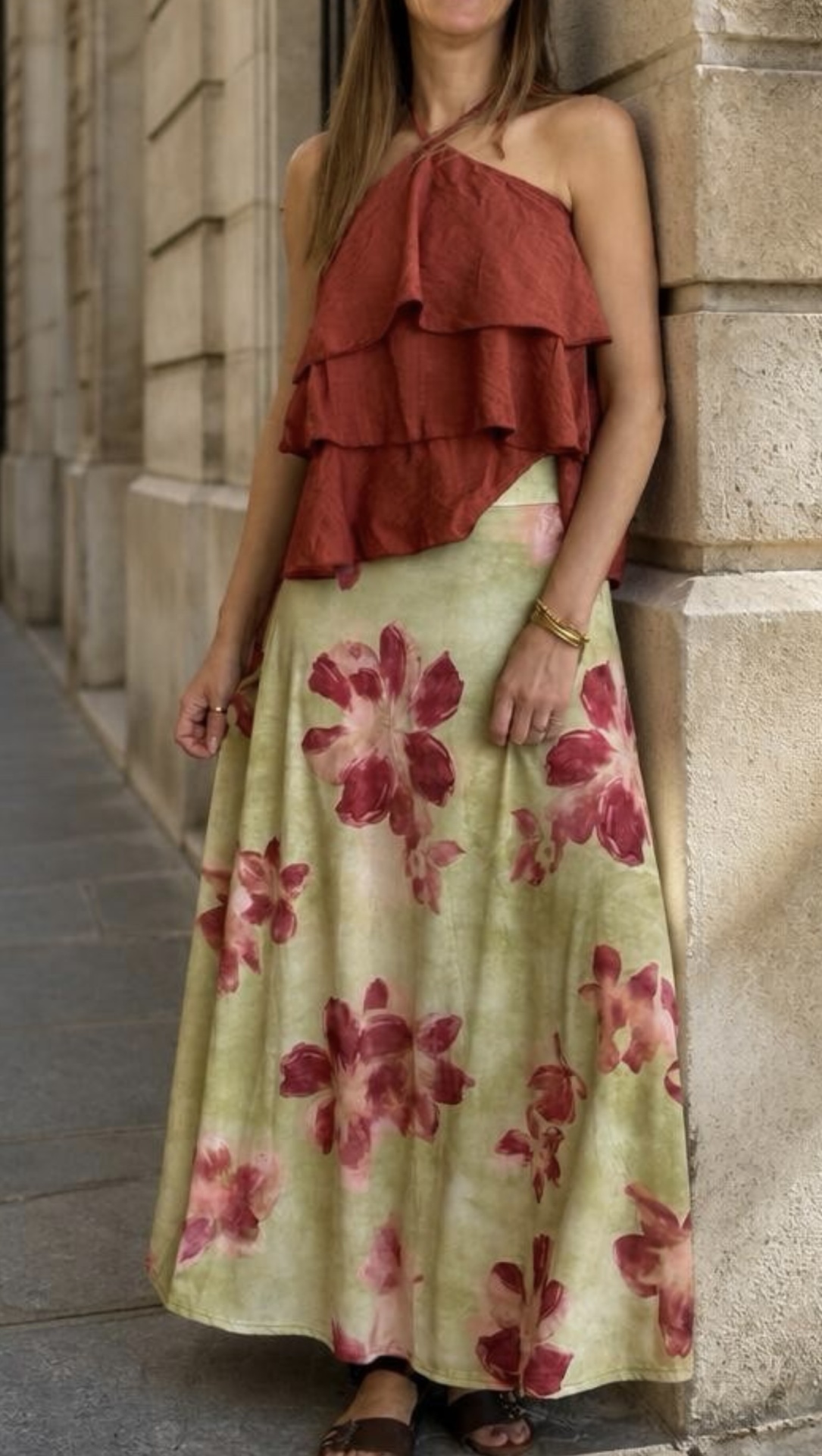 Modelo a usar vestido com top vermelho e saia longa floral verde e vermelha