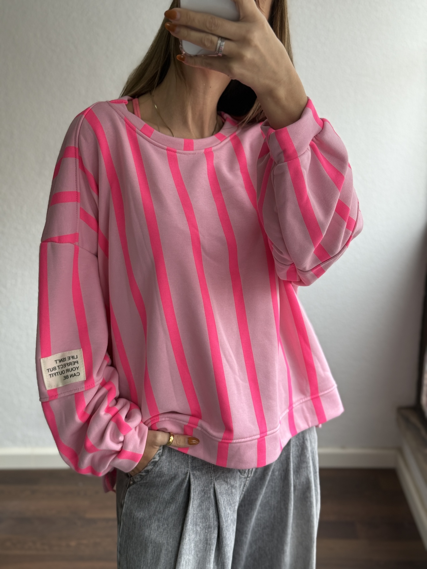 Sweatshirt rosa claro com riscas rosa forte e etiqueta branca no braço
