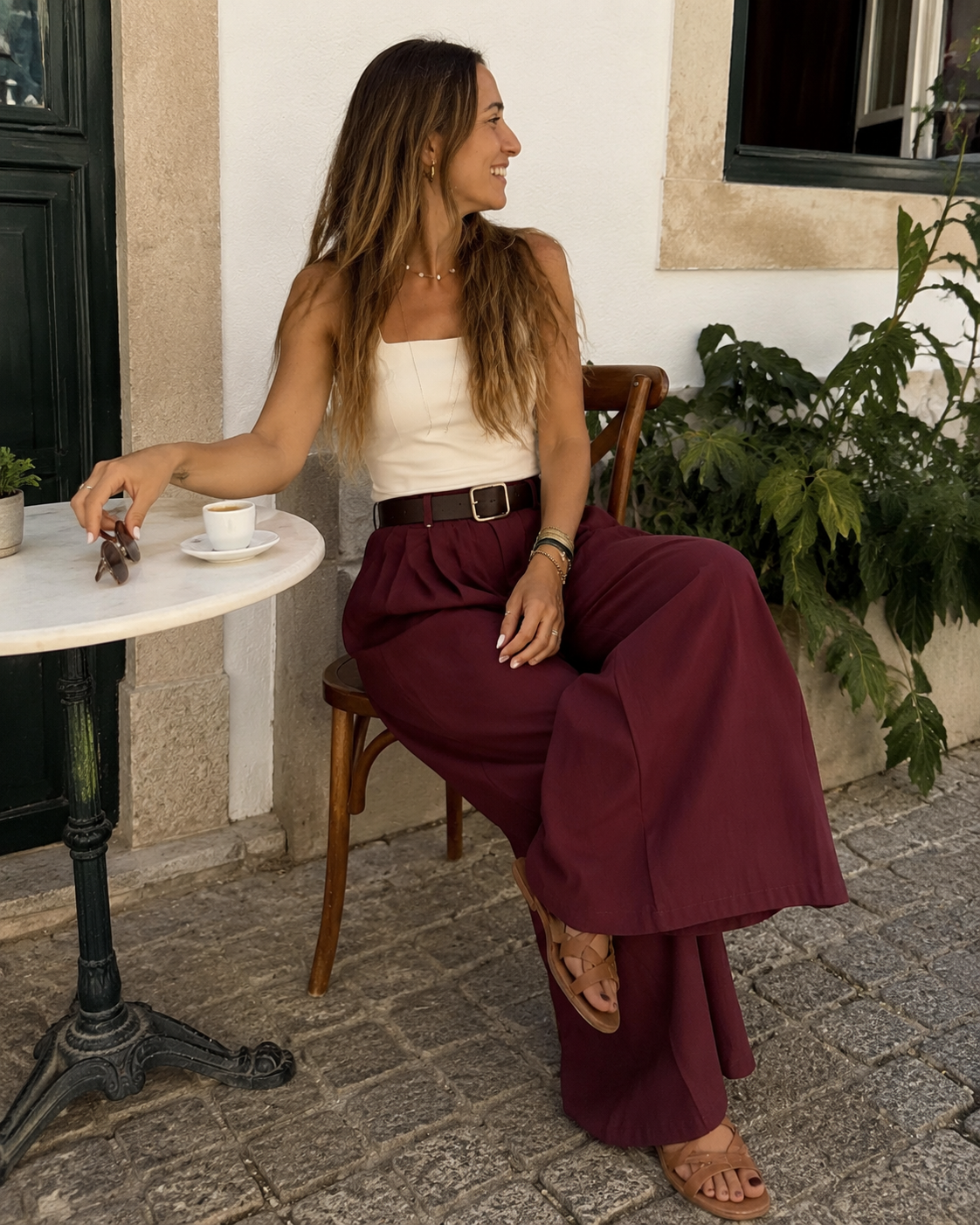 Mulher sentada com roupa casual numa esplanada, com óculos e café na mesa