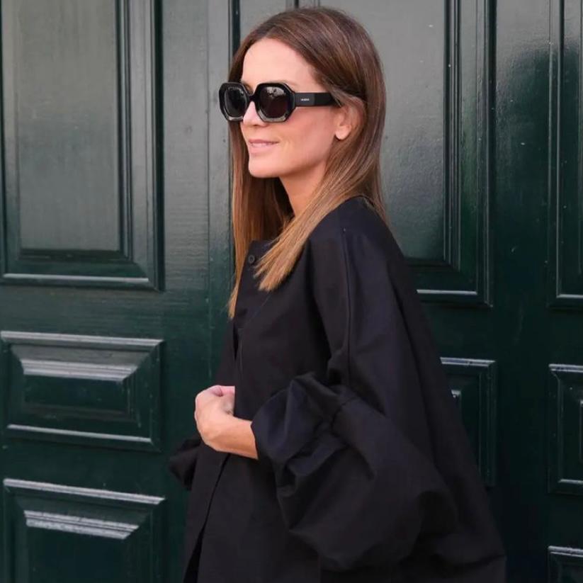 Mulher com blusa preta de mangas largas e óculos de sol pretos