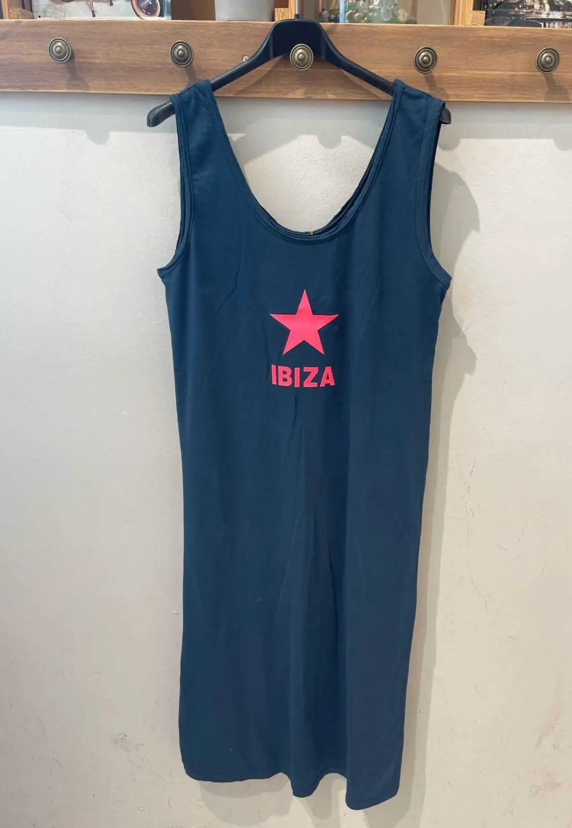 Vestido azul escuro com estrela e texto rosa 'IBIZA' pendurado em cabide