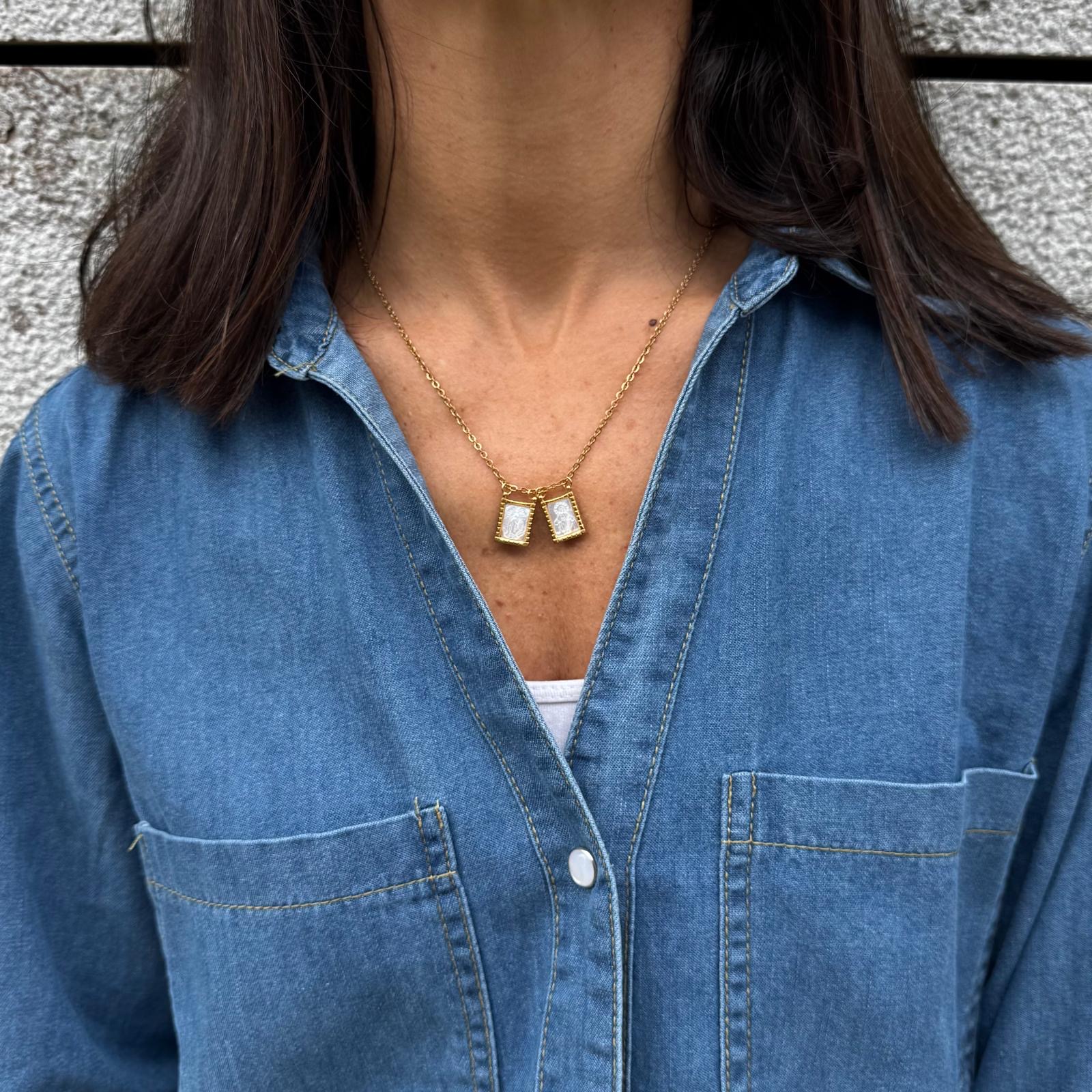 Colar dourado com pendentes em madre-pérola sobre camisa de ganga azul