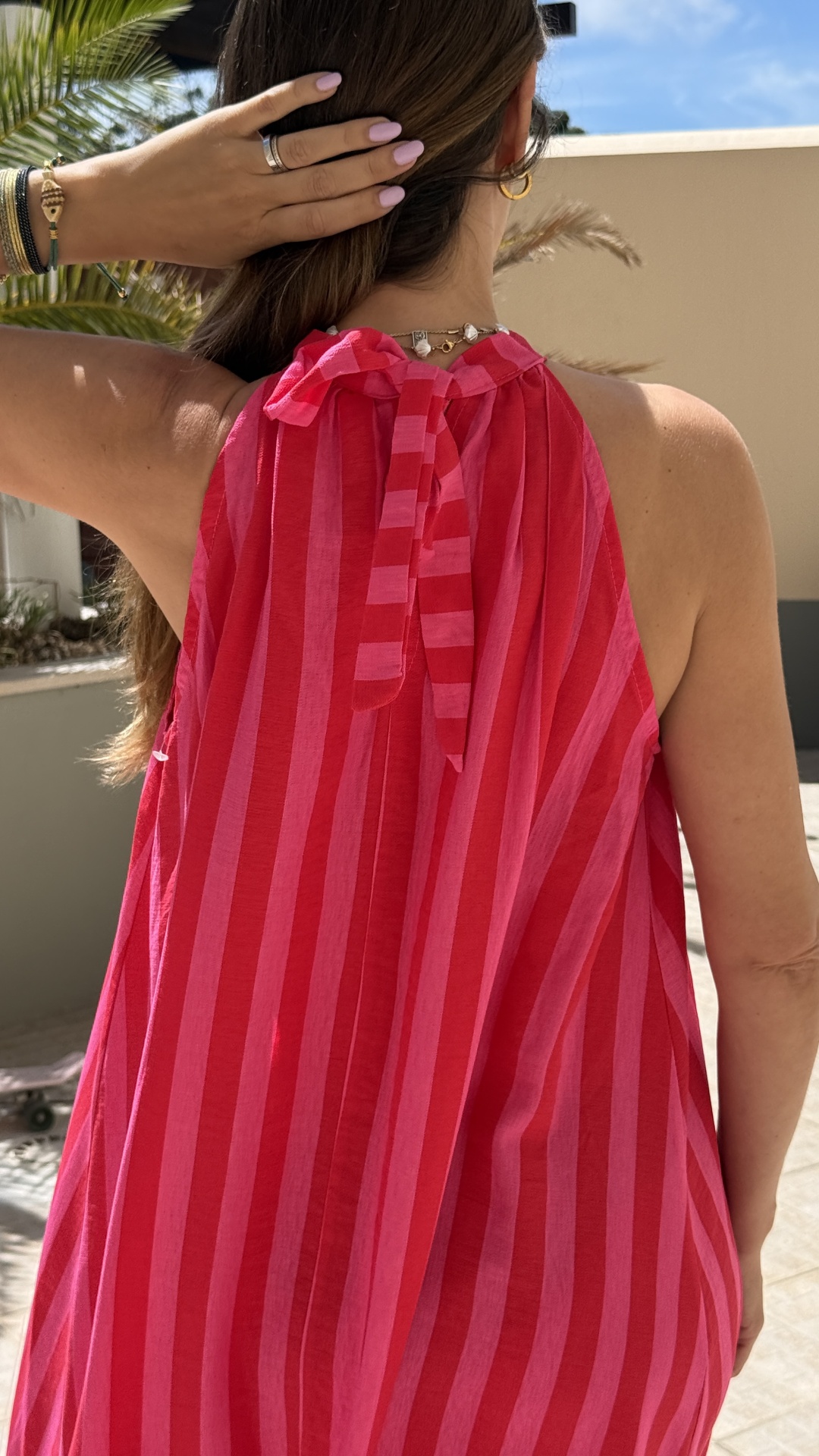 Vestido vermelho e rosa às riscas, amarrado ao pescoço, visto de trás