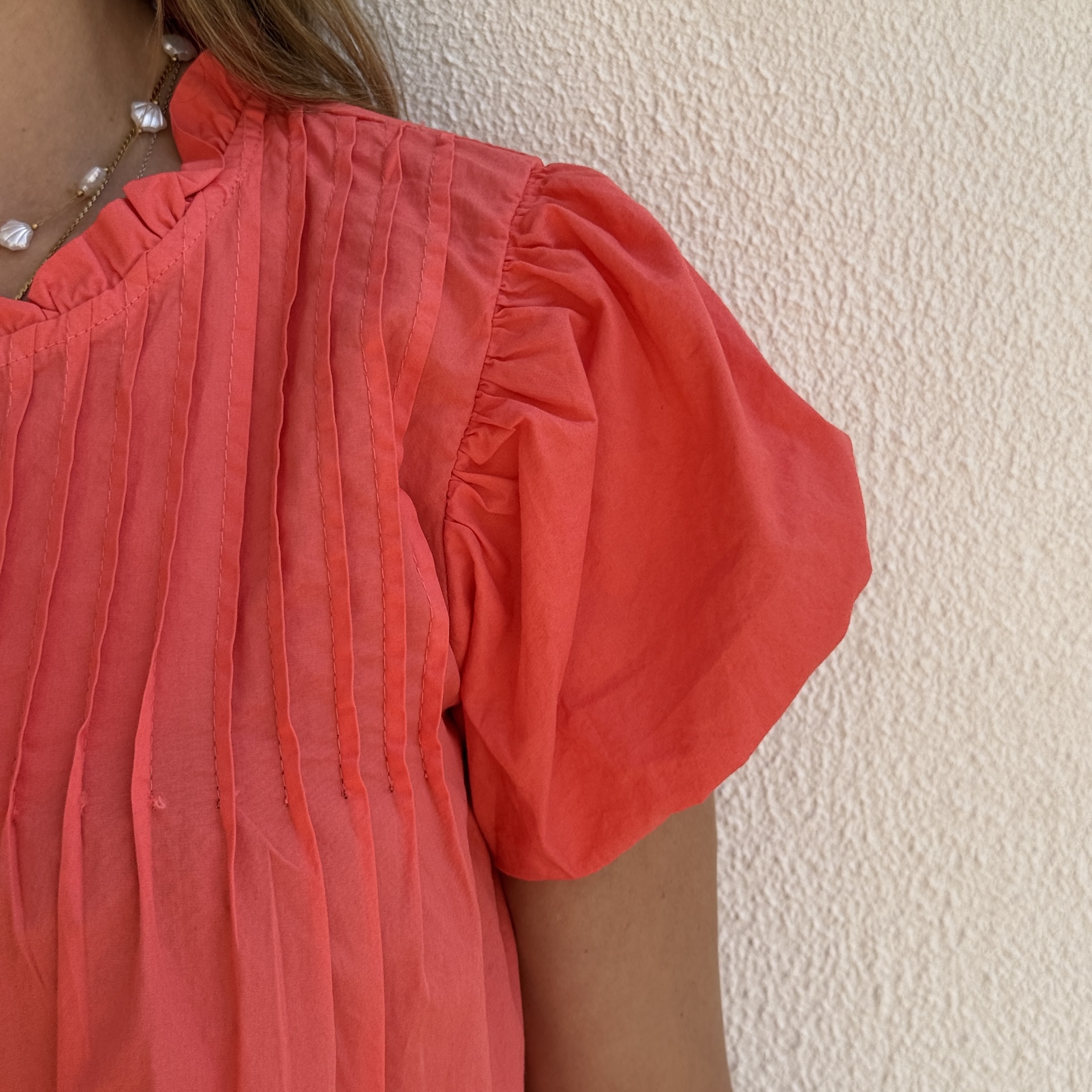 Blusa coral com pregas verticais e mangas bufantes com folhos