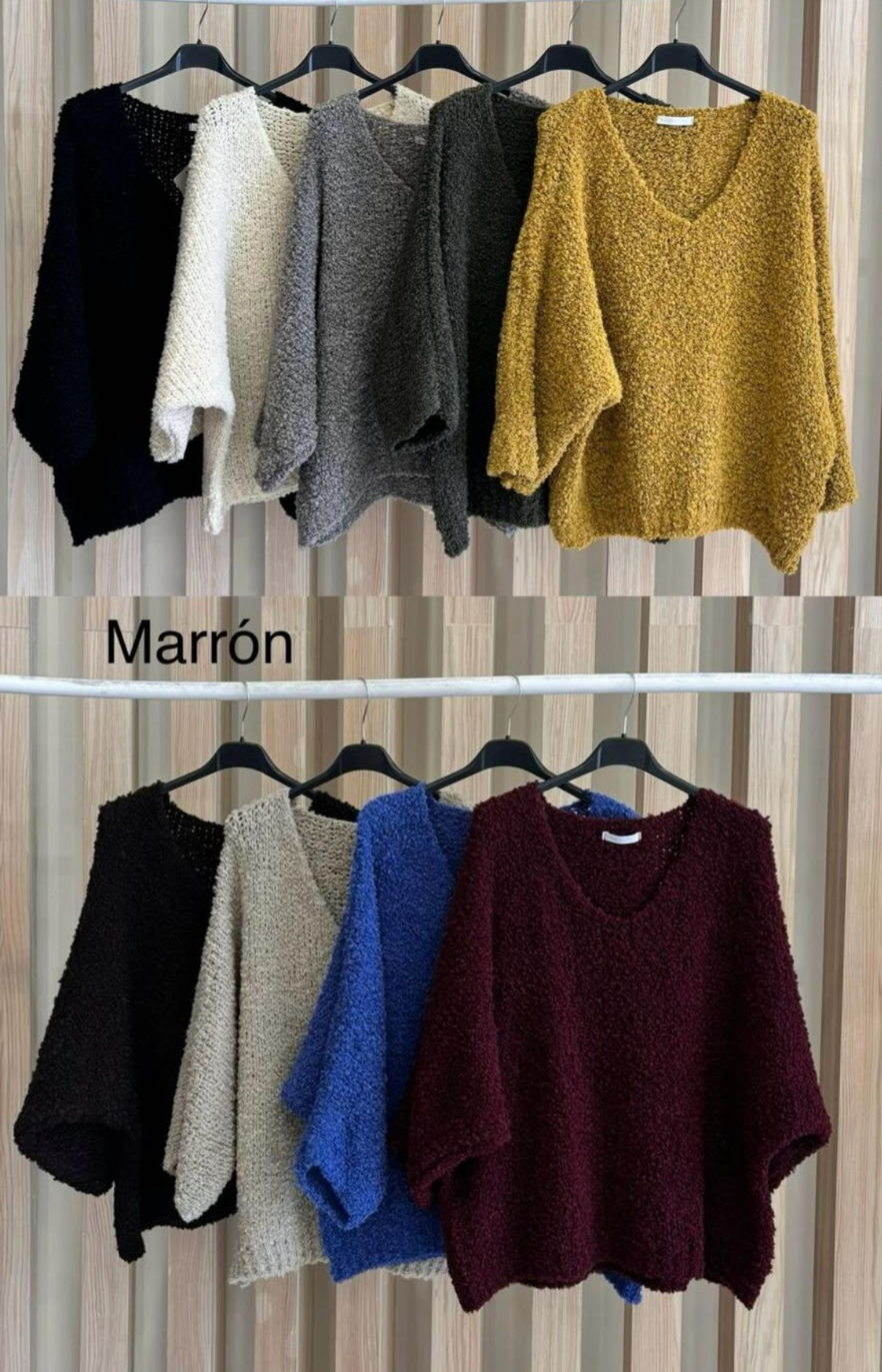 Suéteres de malha grossa em várias cores pendurados em cabides num varão branco