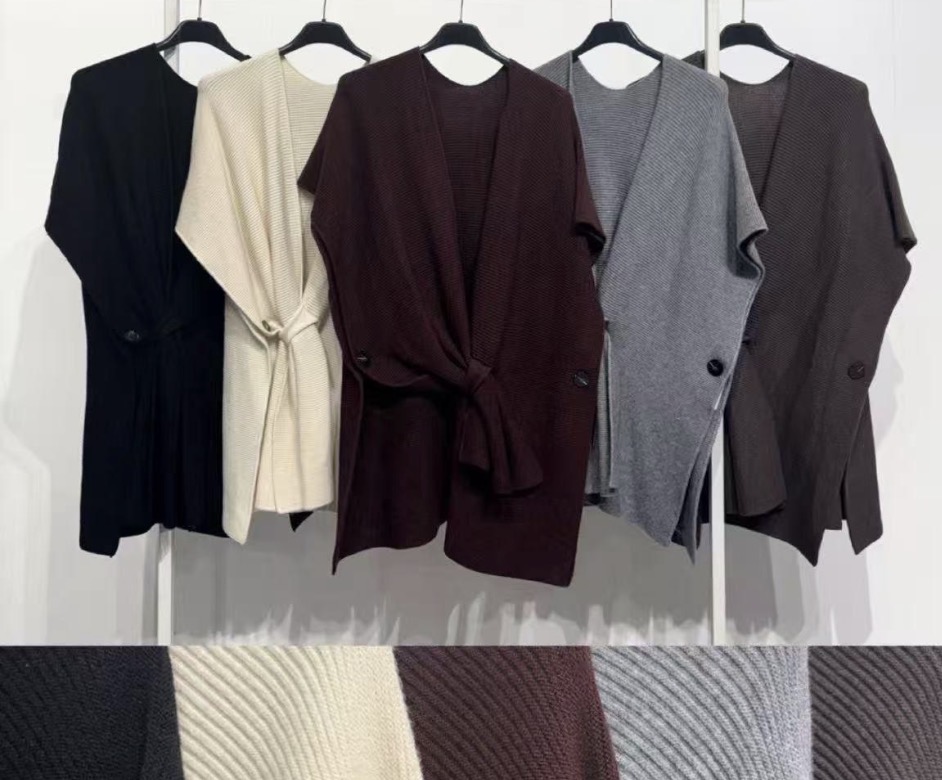 Cinco cardigans de malha em várias cores pendurados em cabides pretos