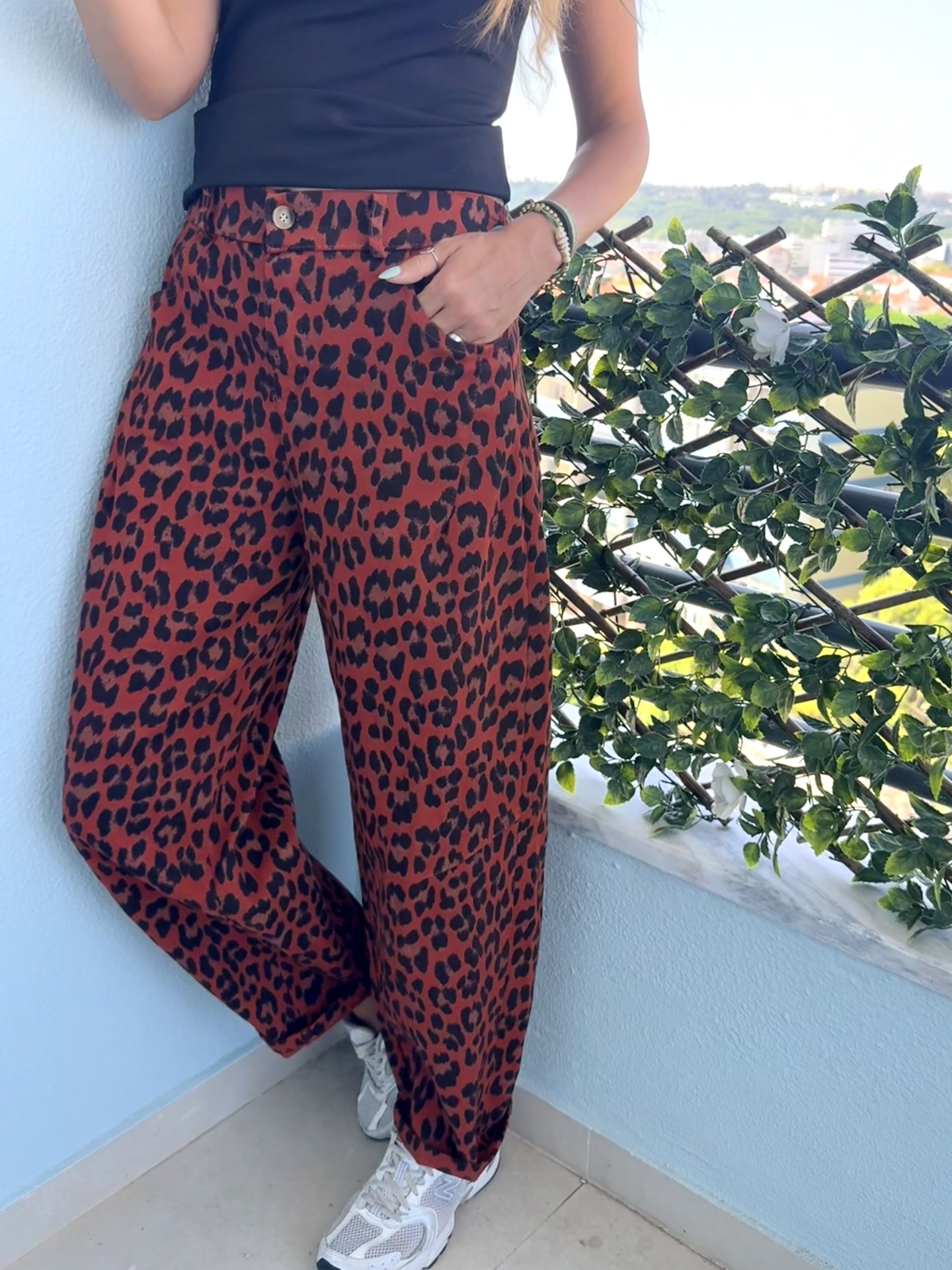 Calças largas com padrão animal print e top preto em ambiente exterior