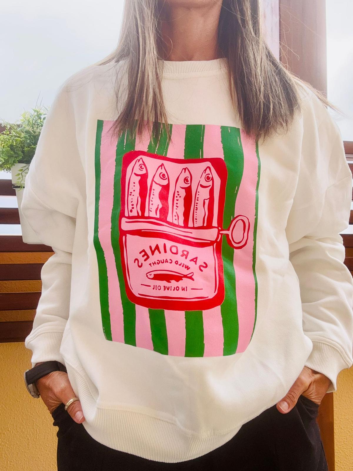 Sweatshirt creme com estampa de lata de sardinhas em cor vermelha sobre riscas verdes e rosas.