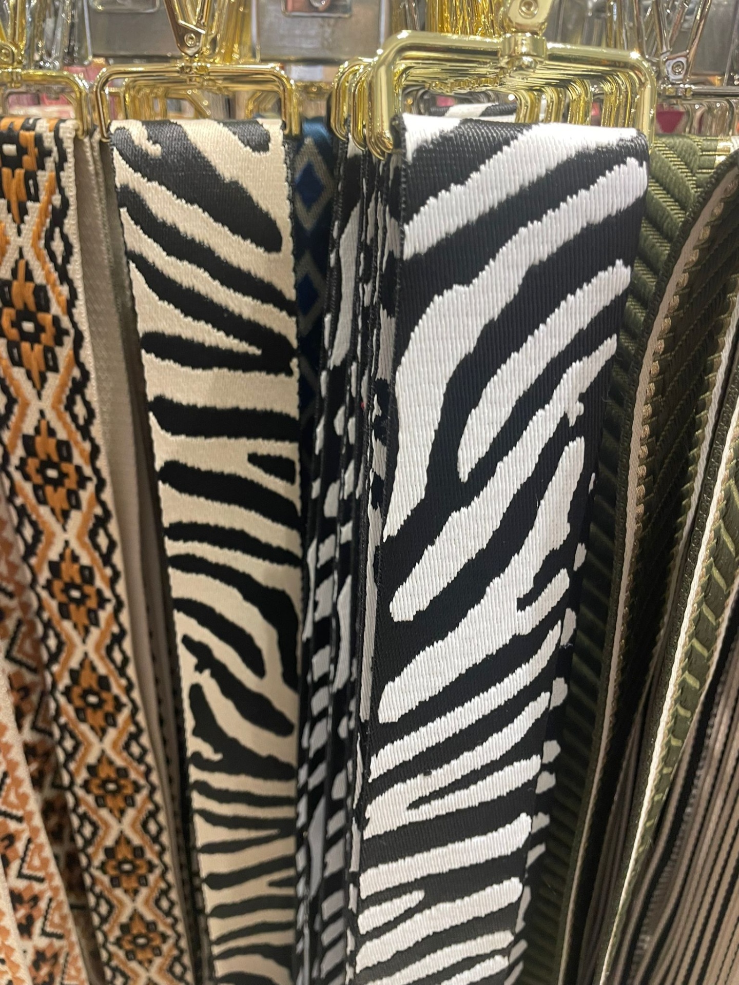 Cintos variados com padrões em tecido e couro pendurados em cabides