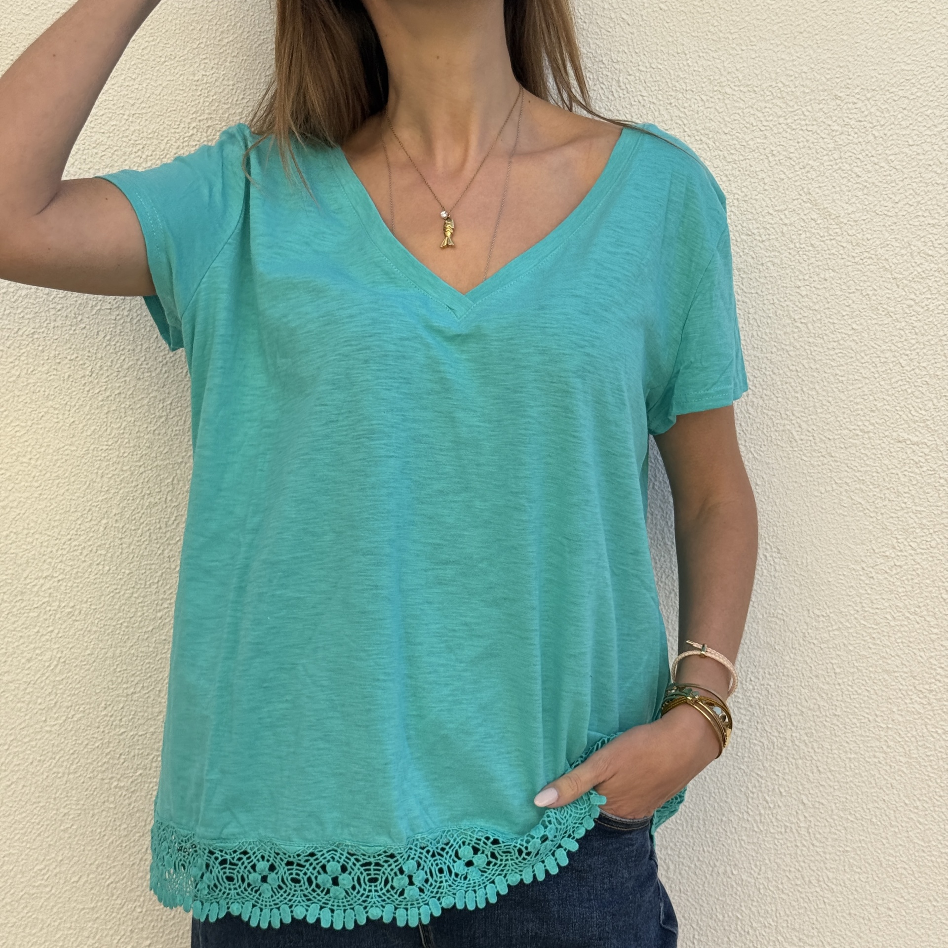 T-shirt verde água com renda na parte inferior e decote em V.
