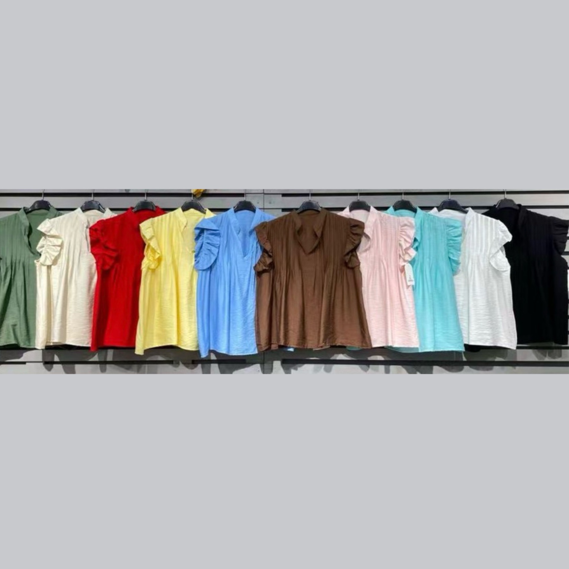 Vestidos coloridos de manga curta com folhos pendurados num painel de exposição.