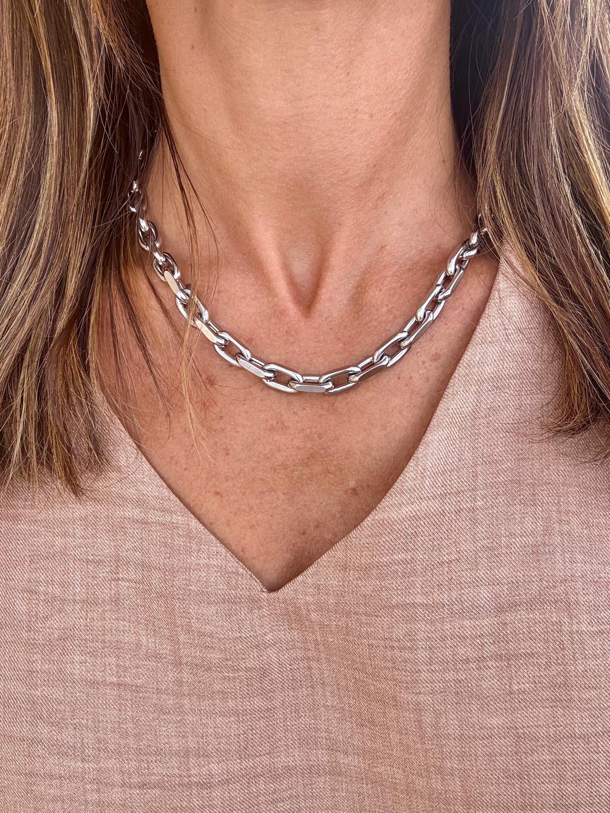 Colar de elos prateados usados por mulher com camisa bege