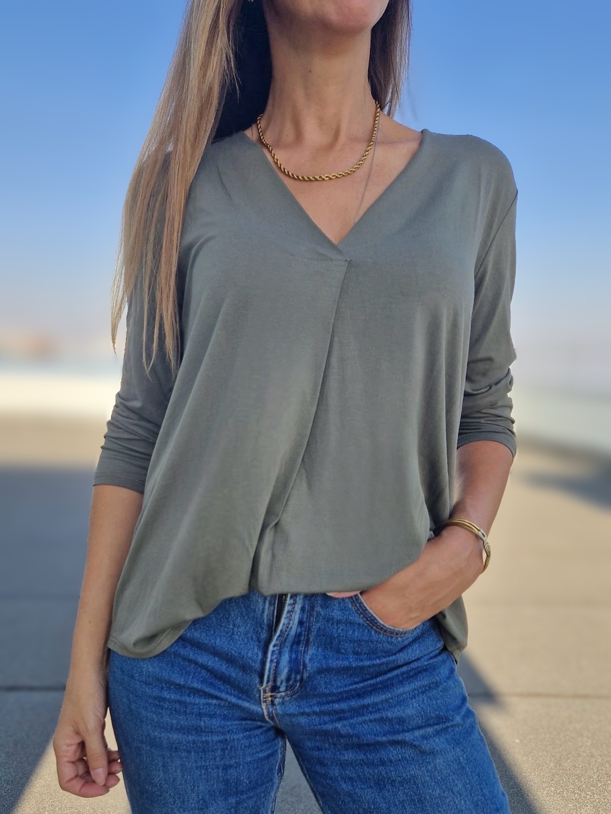 Blusa feminina manga comprida verde-acinzentada com decote em V e jeans azuis