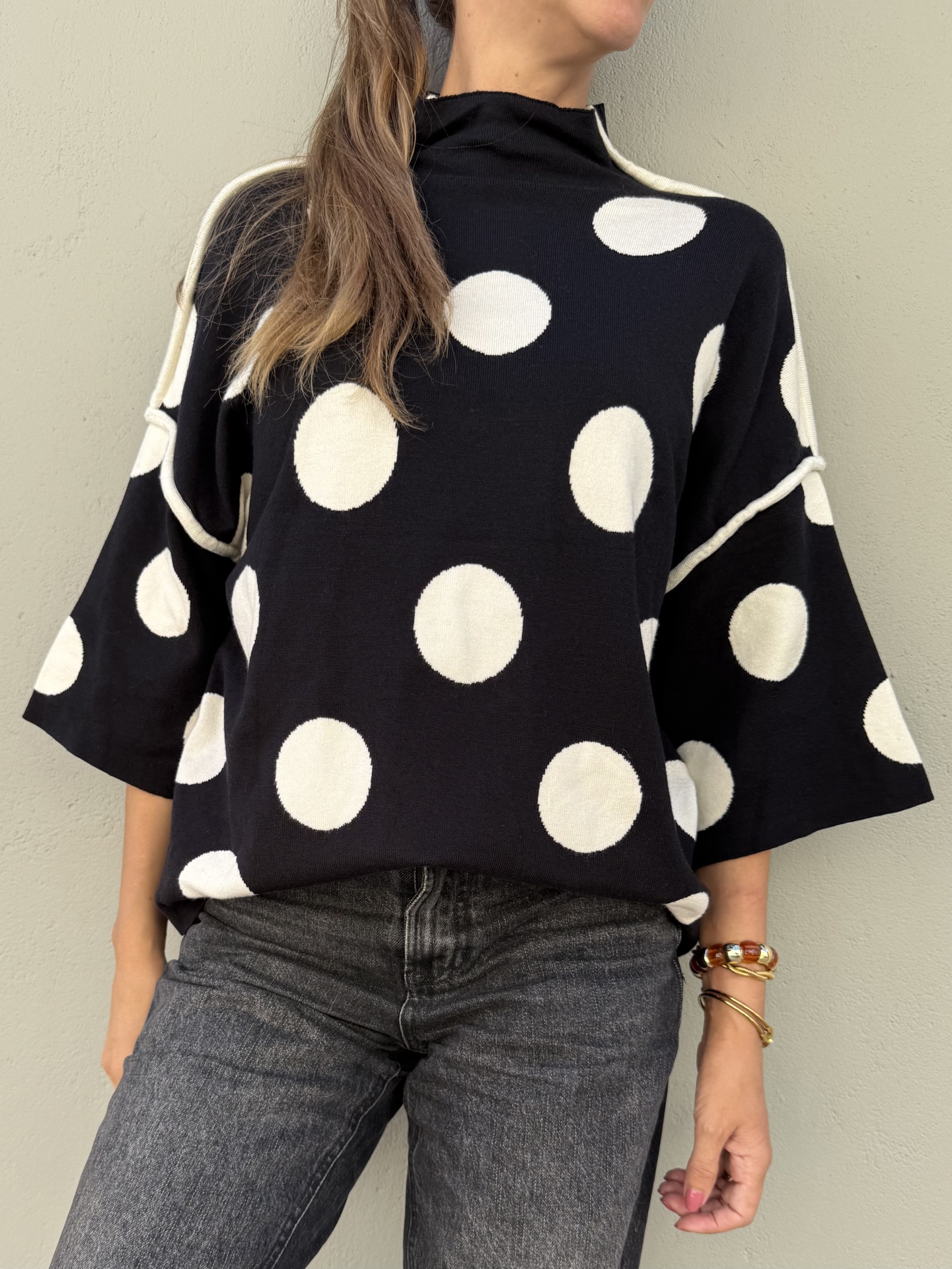 Blusa preta com bolas brancas grandes e calças jeans cinza escuro