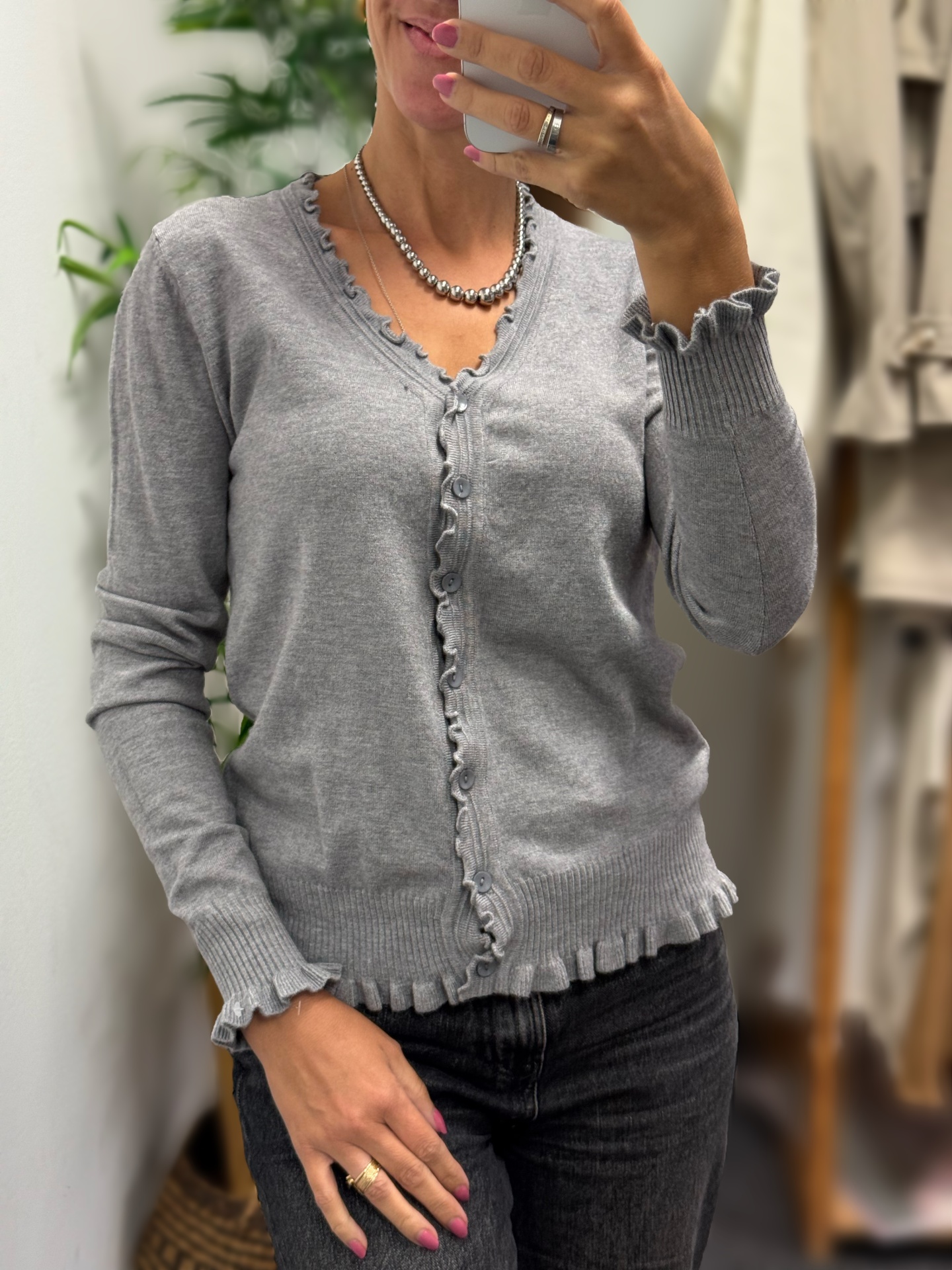 Camisola cinza com botões e acabamentos frisados nas bordas
