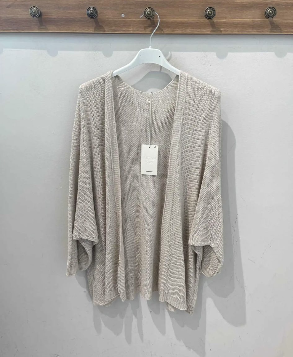 Camisa bege clara de malha com manga larga pendurada num cabide branco