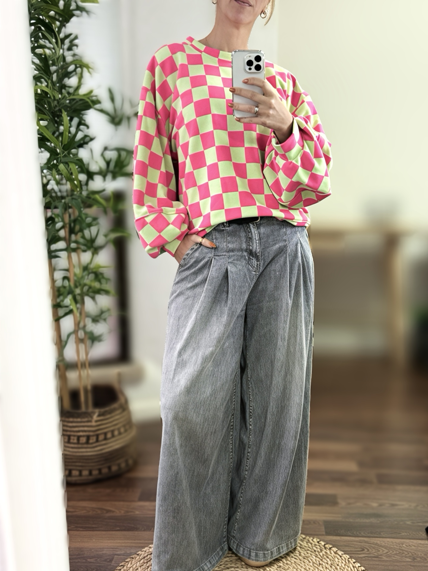 Pessoa com camisola xadrez rosa e verde e calças largas de ganga cinza