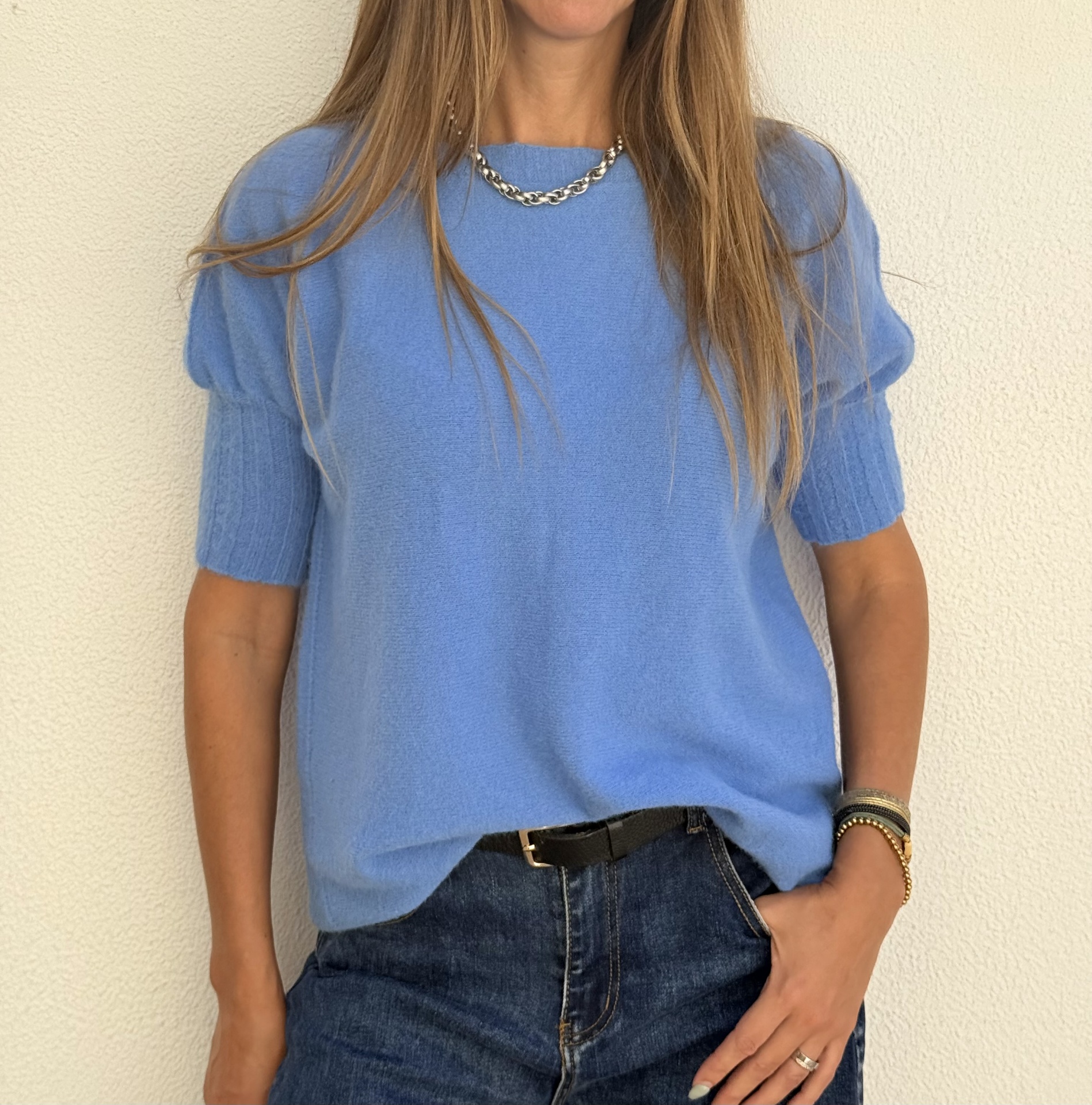 Camisola azul de manga curta com jeans e acessórios